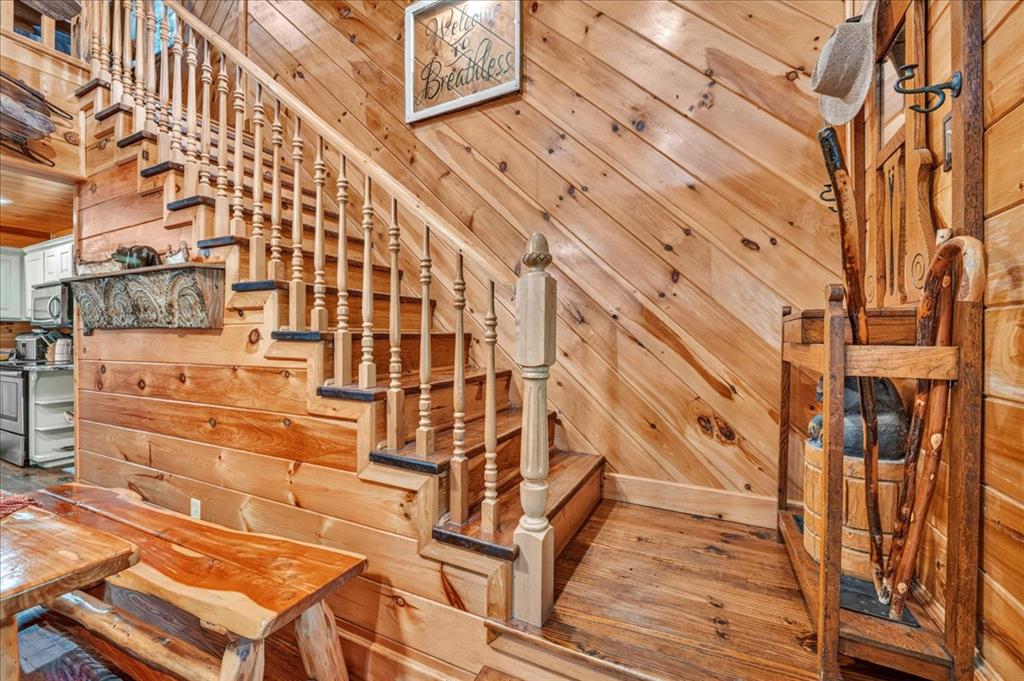 Wood-paneled cabin interior with a turned-wood staircase, rustic dining table, and Western-style decor.