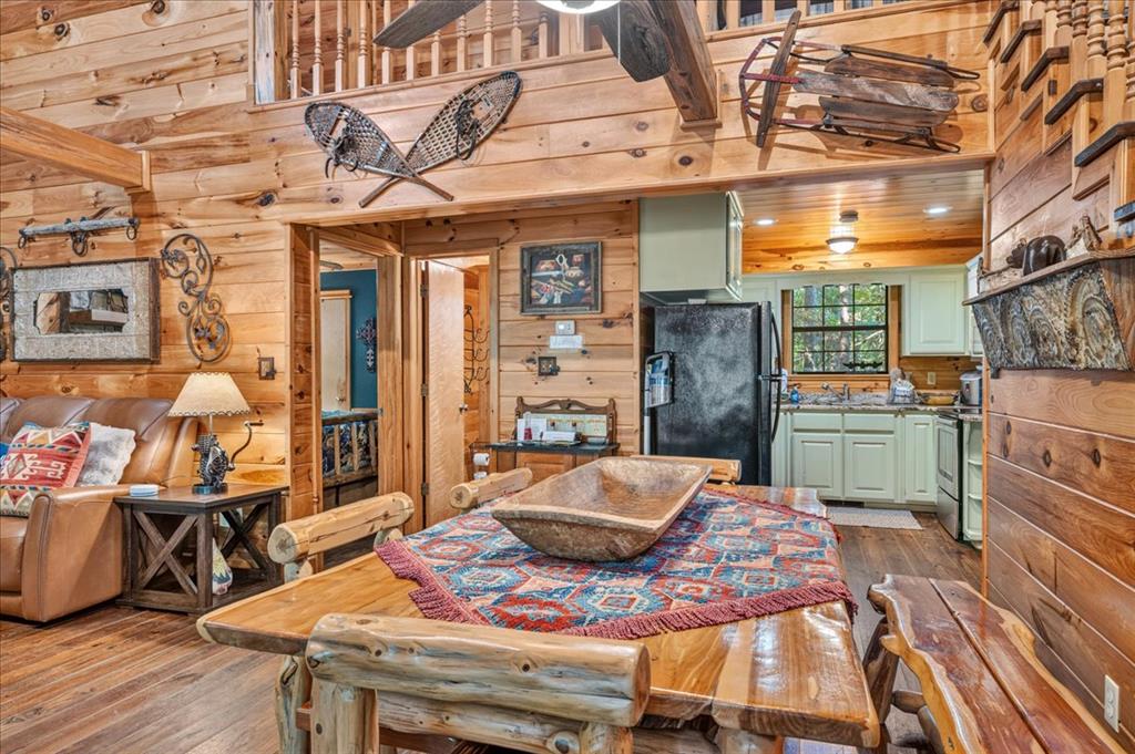 Rustic cabin dining area with a log table, leather sofa, and compact kitchen.