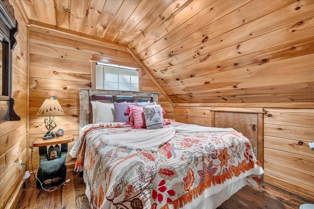 Cabin bedroom with a sloped wood ceiling and colorful floral bedding.