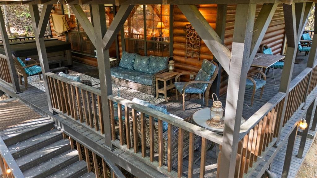 Covered cabin deck with wicker seating, blue patterned cushions, railings, and stairs.