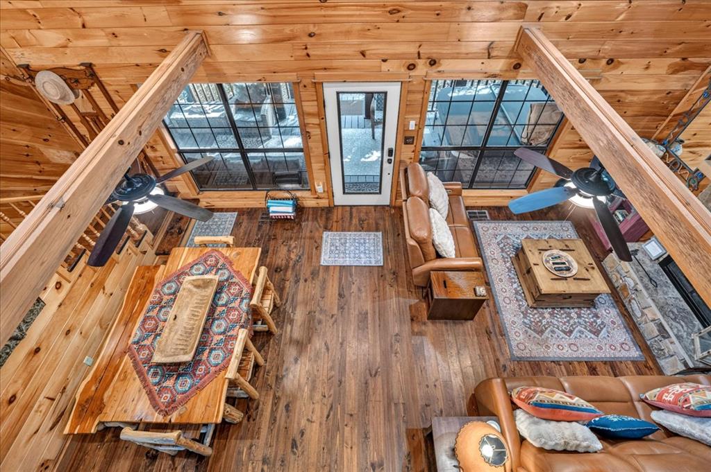 Open-concept cabin living and dining area with exposed beams, large windows, and leather seating.