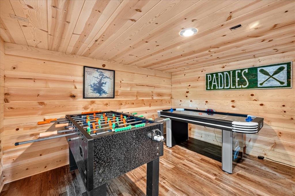 Wood-paneled game room with foosball and air hockey tables.