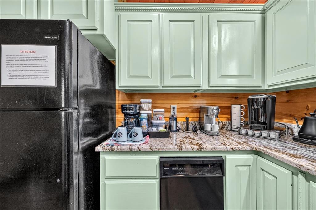 Kitchen coffee station with mint-green cabinets, granite counters, and a wood backsplash.