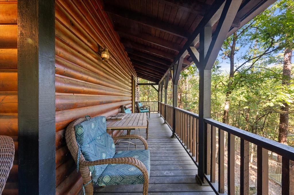 Covered cabin porch with cushioned wicker chairs overlooking leafy woodland.