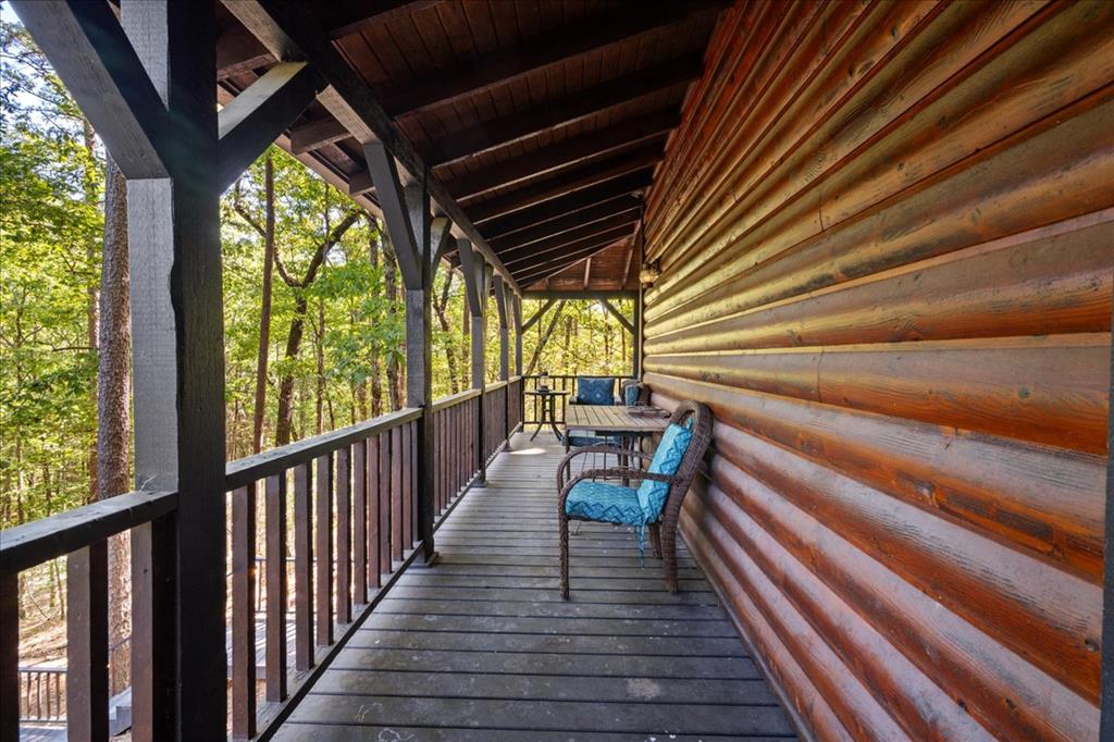 Covered cabin porch with blue-cushioned chairs overlooking leafy woods.