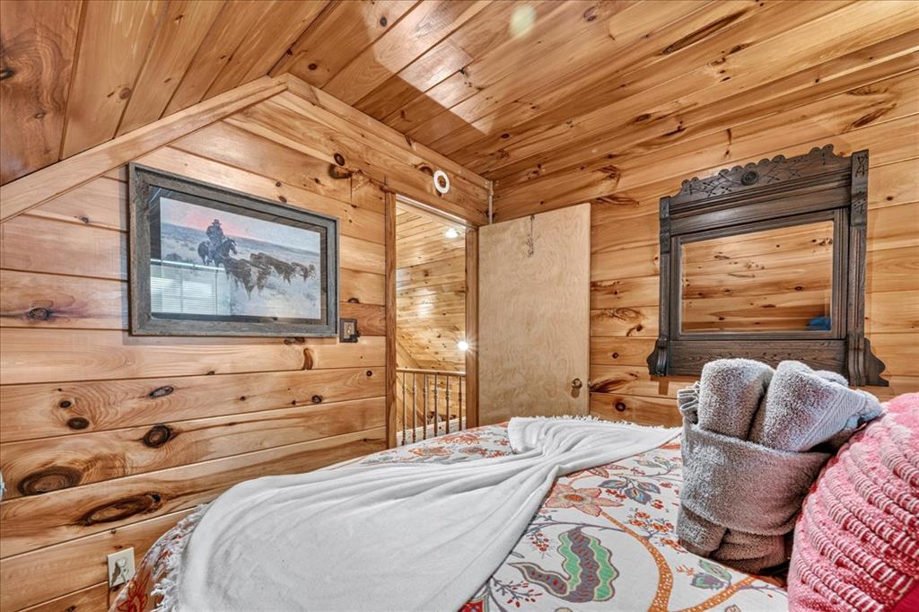 Bedroom with knotty pine walls, a wood-plank ceiling, and a bed with folded towels.