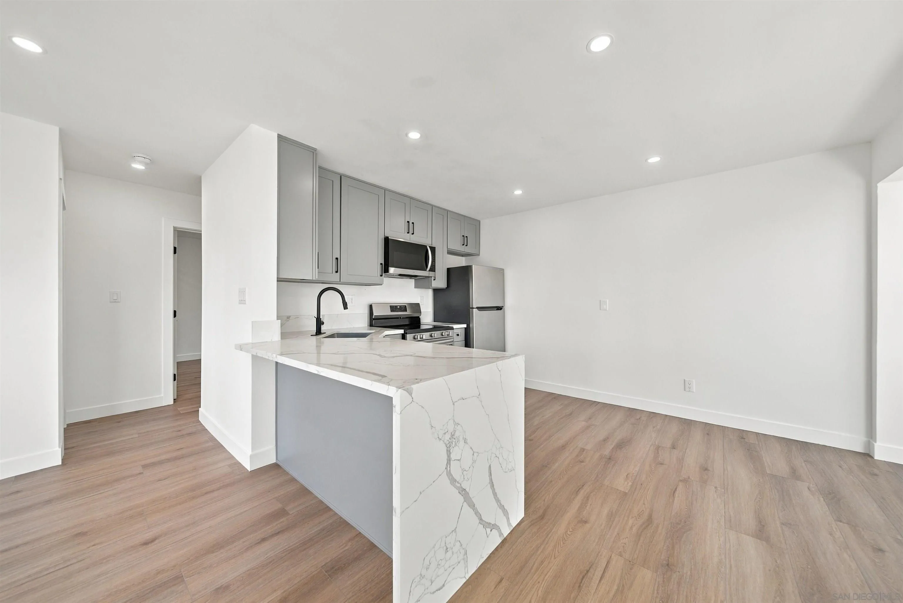 Kitchen with gray cabinets, stainless steel appliances, and a marble-look waterfall island.