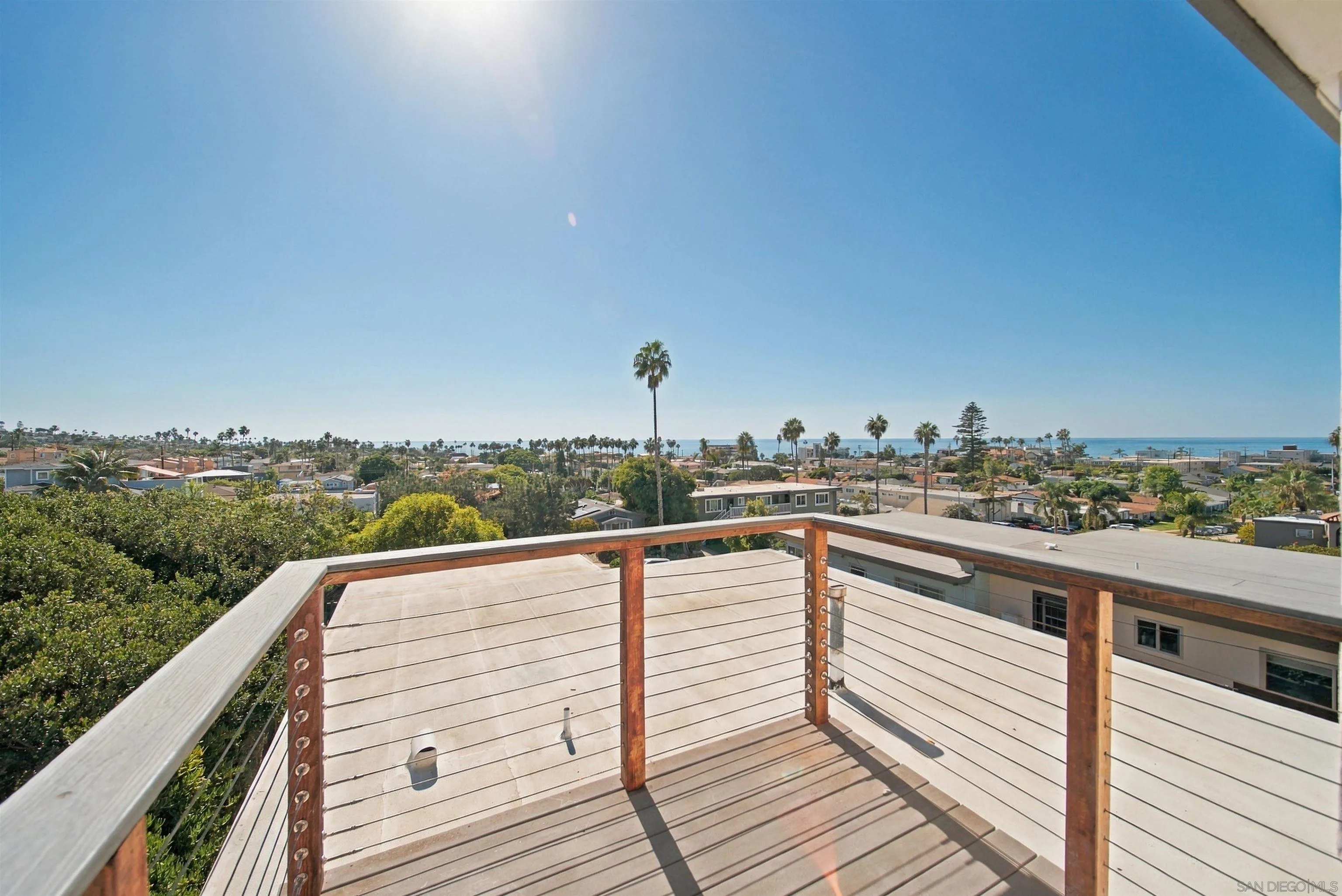 Rooftop deck overlooking the Pacific Ocean, palm trees, and a coastal neighborhood.