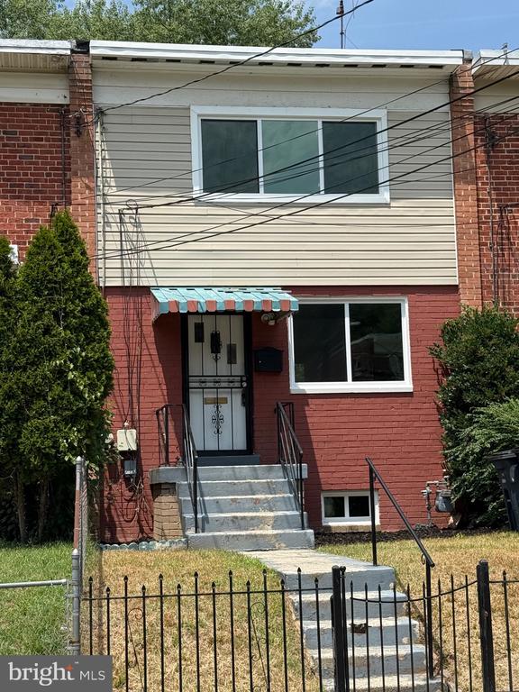 Two-story brick-and-siding home with a fenced front yard and central entry steps.