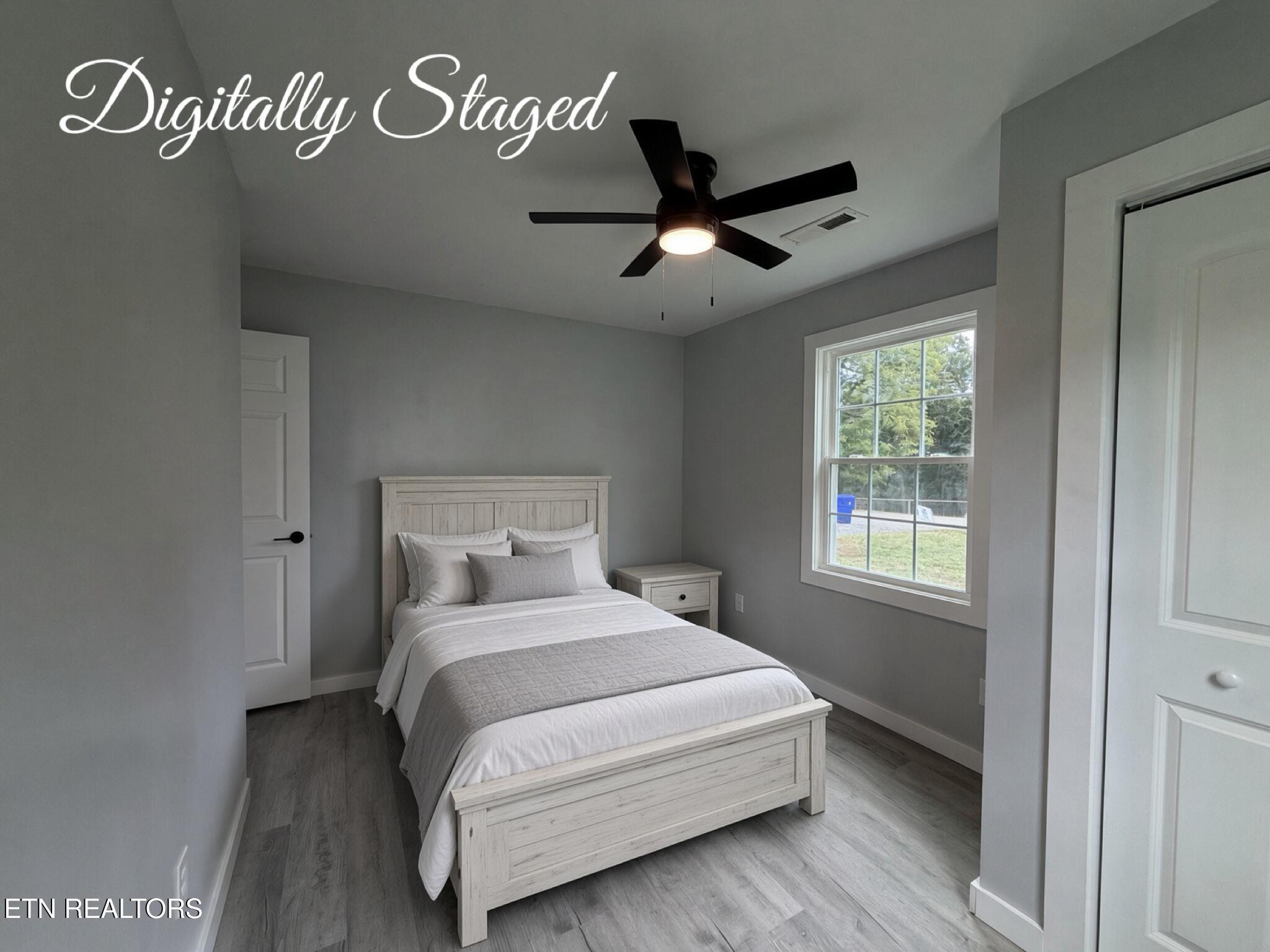 Bedroom with a white wooden bed, gray walls, and a window overlooking greenery.