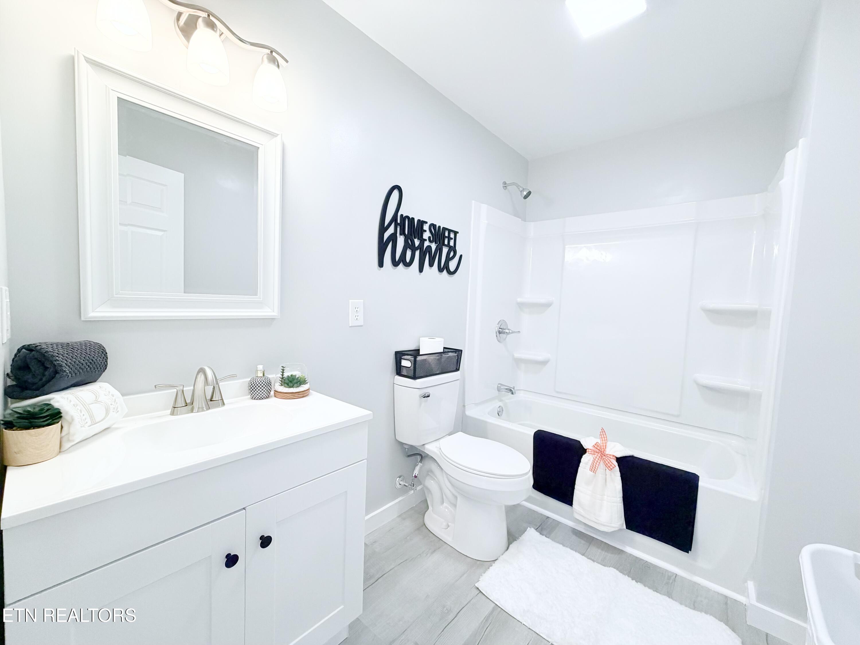 Bright bathroom with a white vanity, toilet, and tub-shower surround.