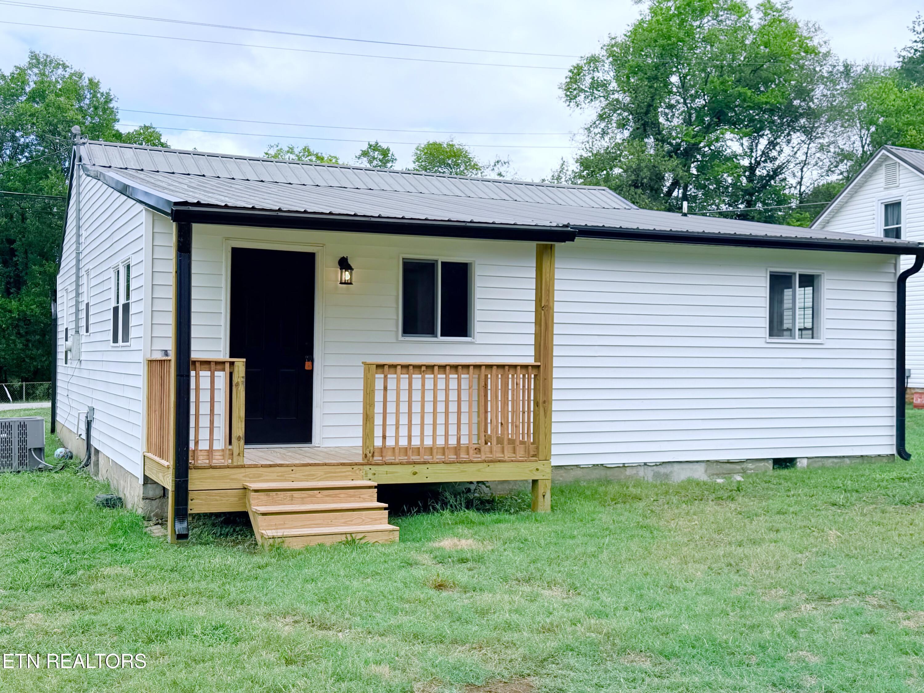 White single-story house with a gray metal roof and a small wooden front porch.