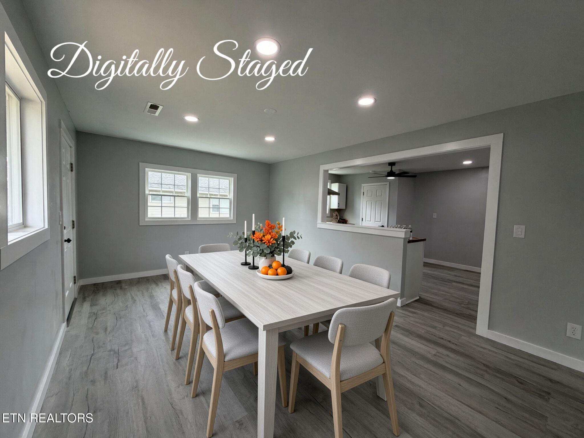 Dining room with a long light-wood table, upholstered chairs, and a wide kitchen pass-through.