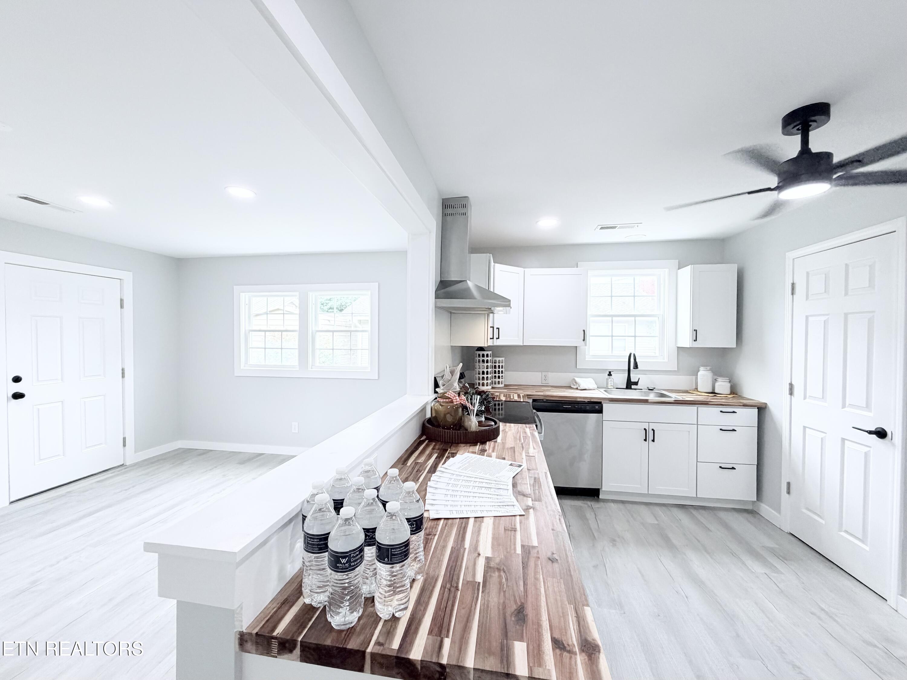 Bright kitchen with white cabinets, stainless appliances, and a long striped wood island.