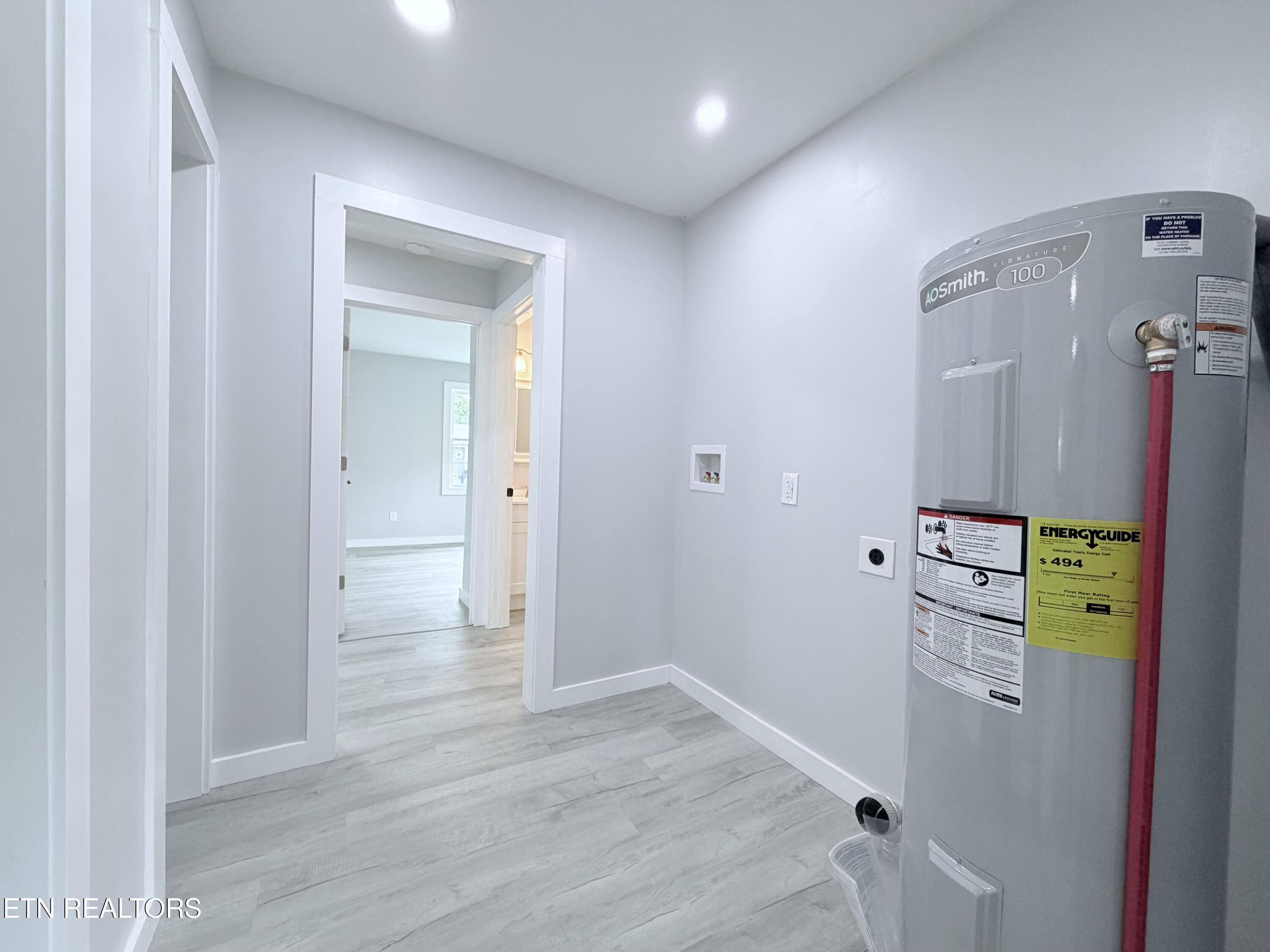Utility room with a large gray water heater and a doorway to the adjoining room.