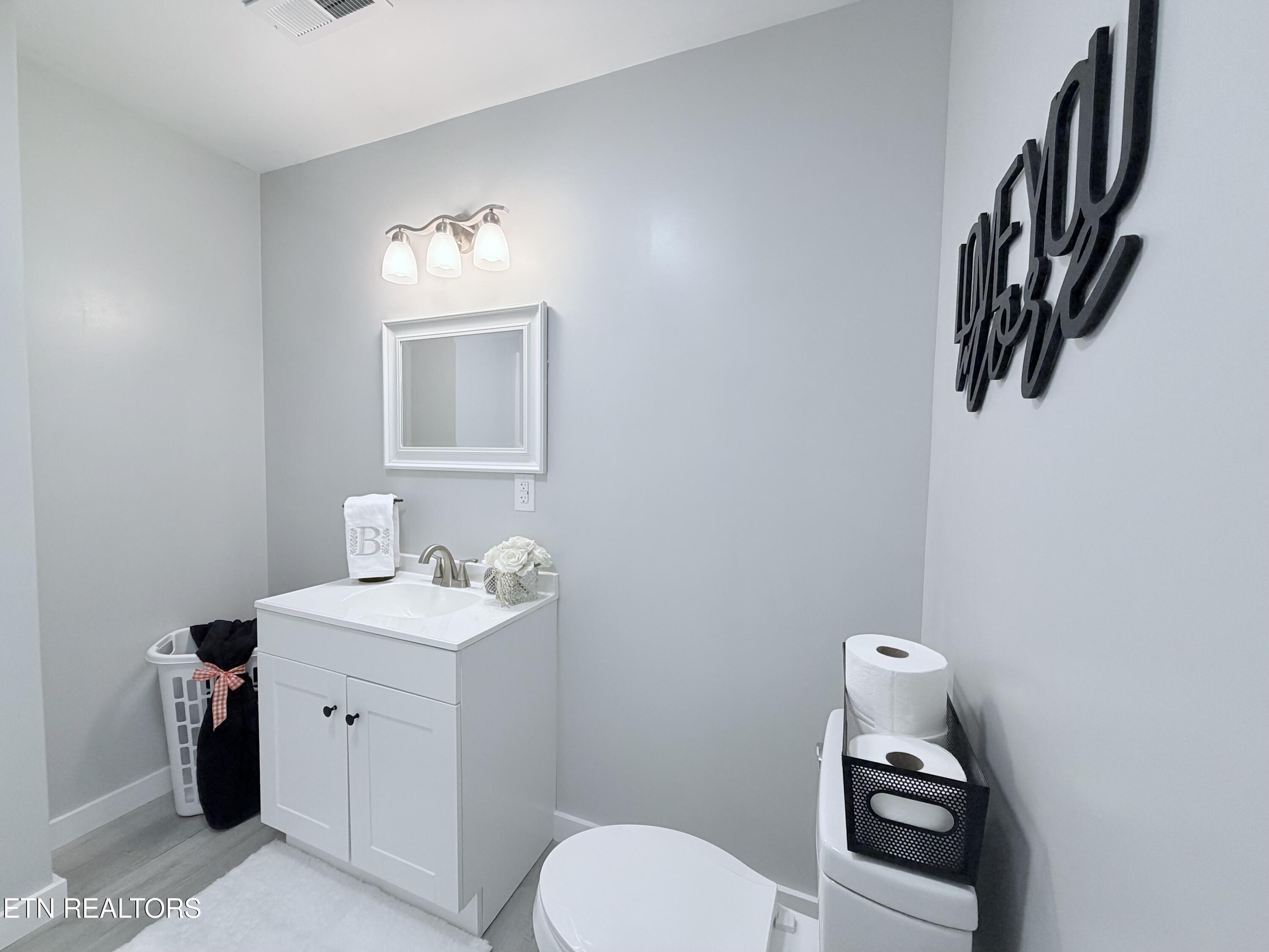 Bathroom with a white vanity, framed mirror, gray walls, and toilet.