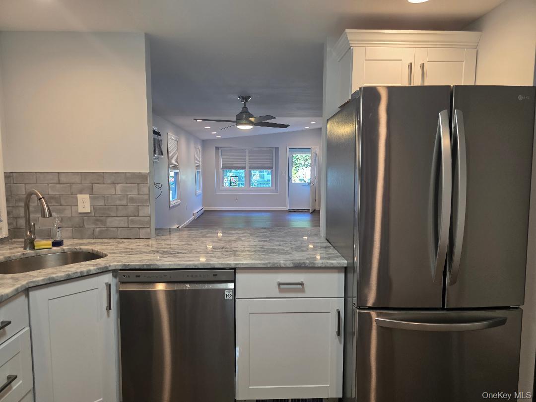 Kitchen with white cabinets, stainless steel appliances, and a view into an open living area.