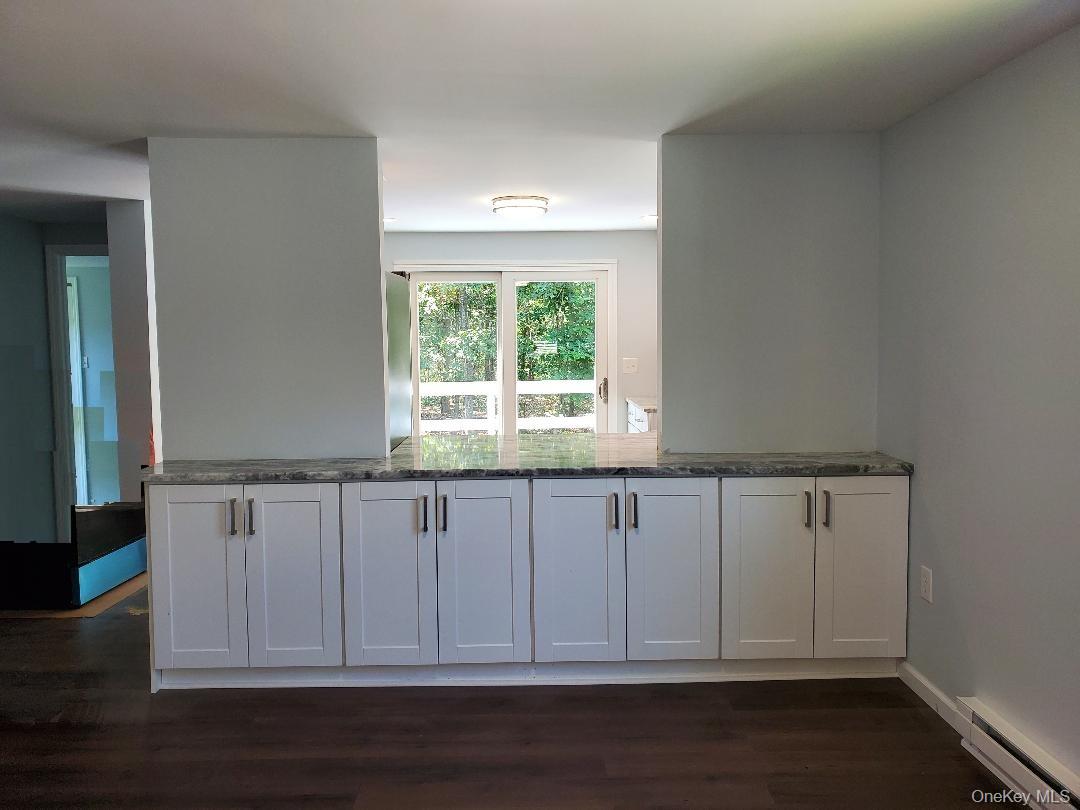 Kitchen with white cabinets, a dark stone countertop, and glass doors overlooking greenery.