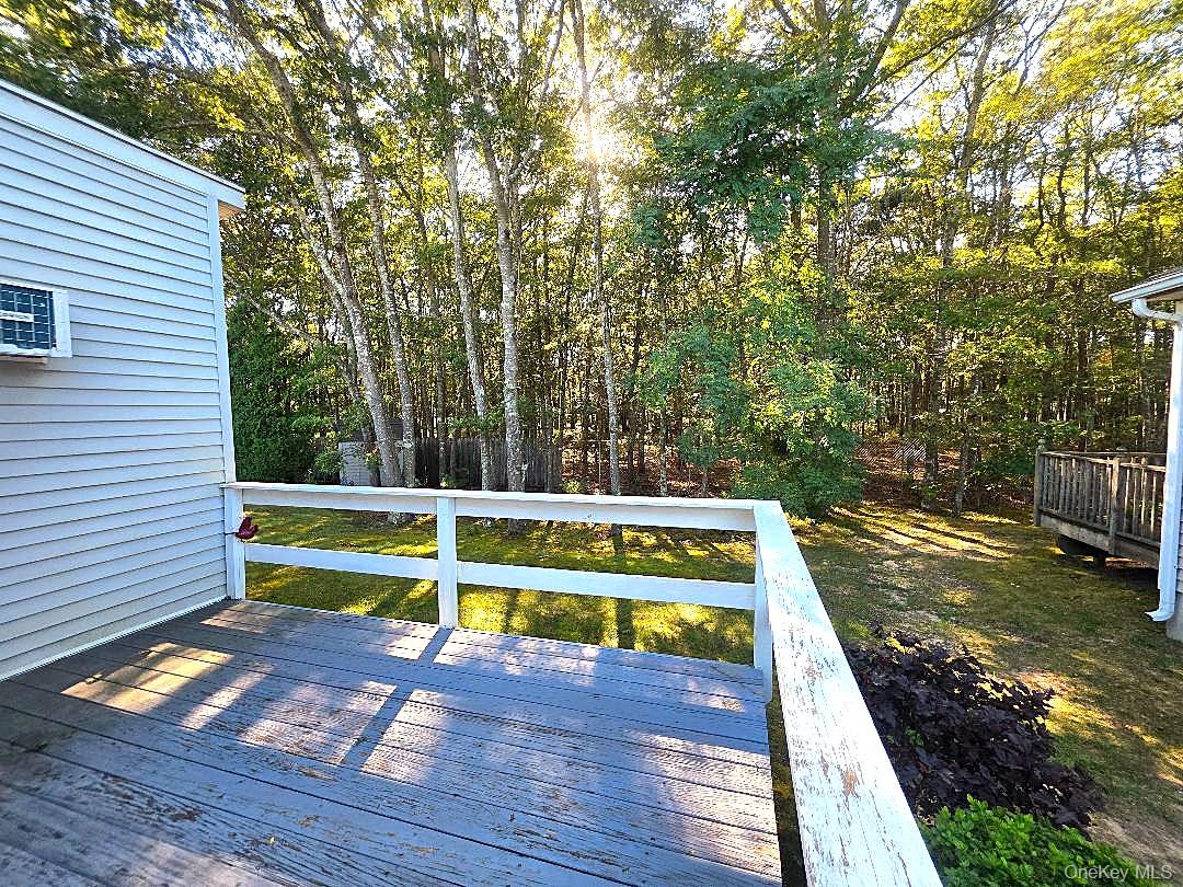 Wooden deck with white railings overlooking a tree-lined backyard in autumn.