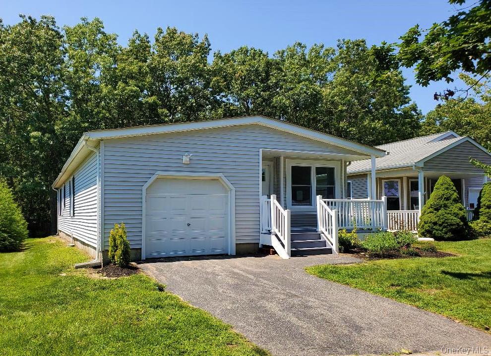 Light blue single-story home with an attached garage, covered porch and paved driveway.