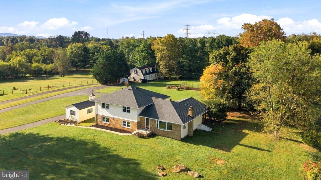 Aerial view of a two-story home surrounded by a broad lawn and autumn trees.