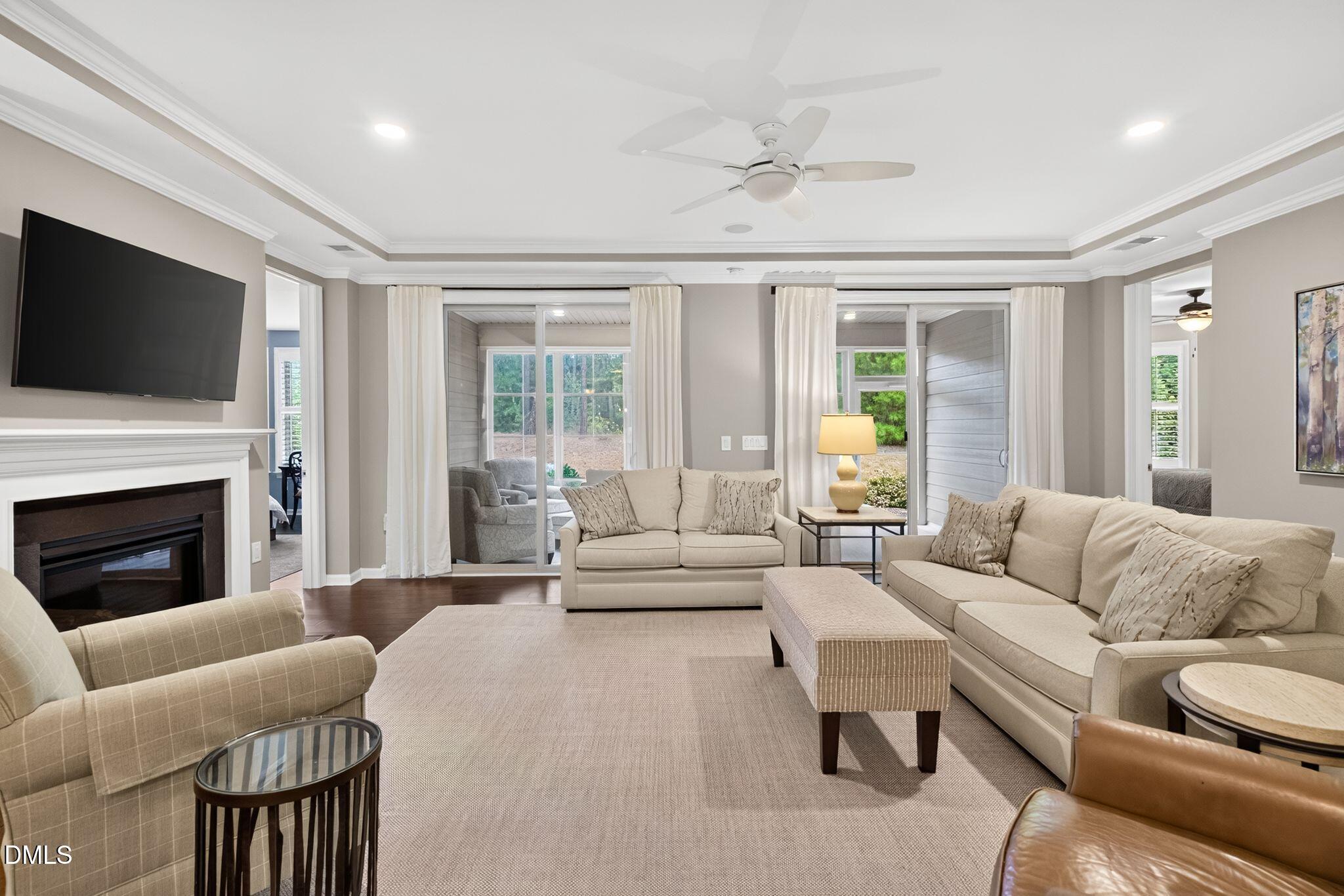 Living room with neutral seating, a fireplace, mounted television, and sliding glass doors.