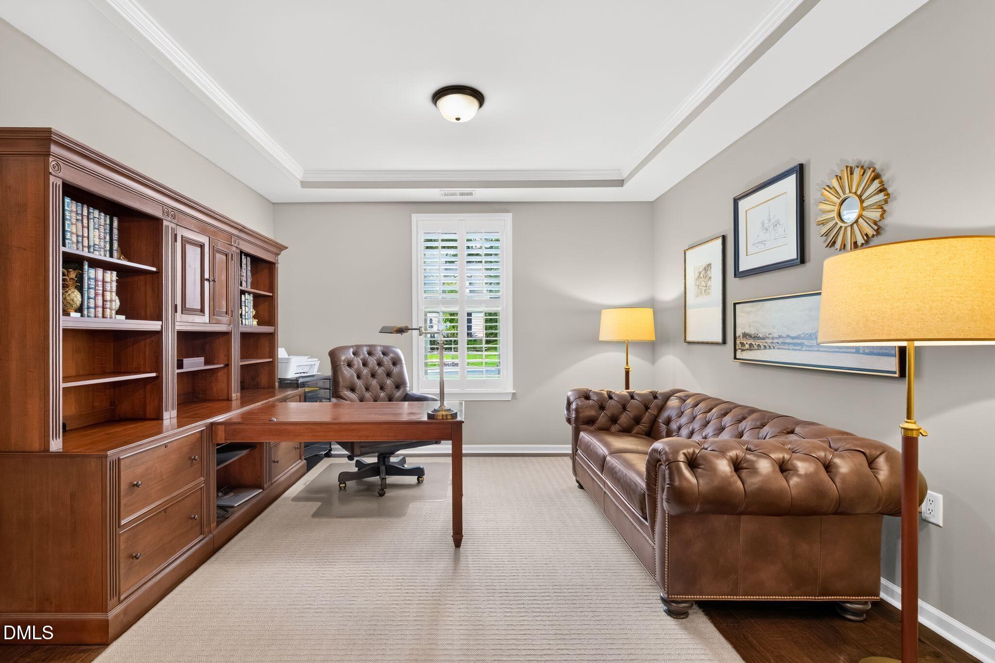 Furnished home office with built-in wood bookcases, a desk, and tufted leather sofa.