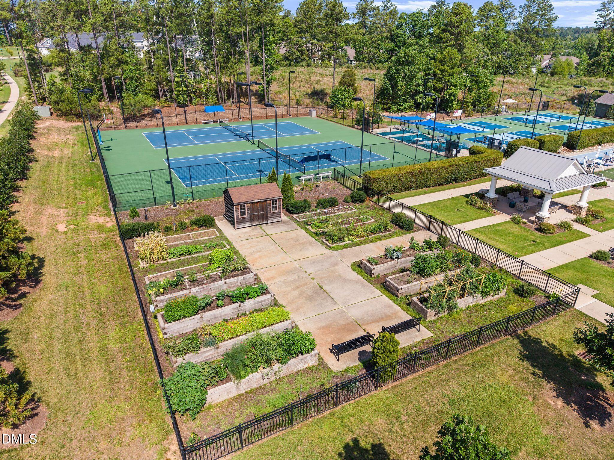 Community tennis courts, raised garden beds, and a pavilion viewed from above.