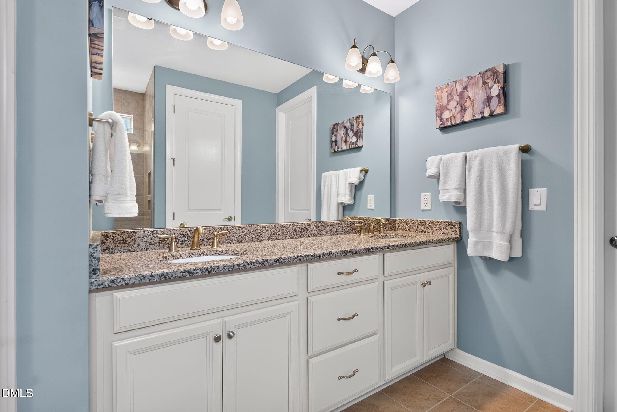 Bathroom with a white double vanity, speckled granite countertop, and blue walls.