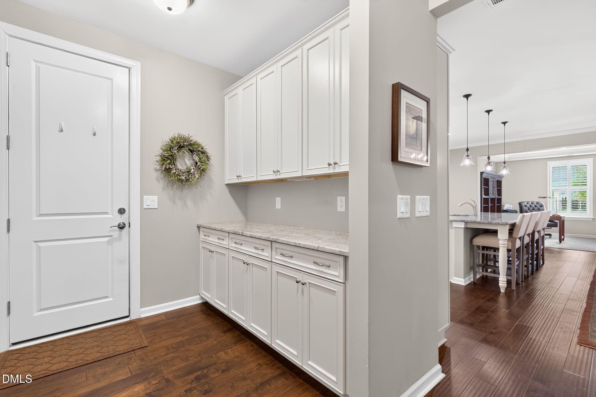 Built-in white cabinetry and stone counter by the entry, with a dining area beyond.