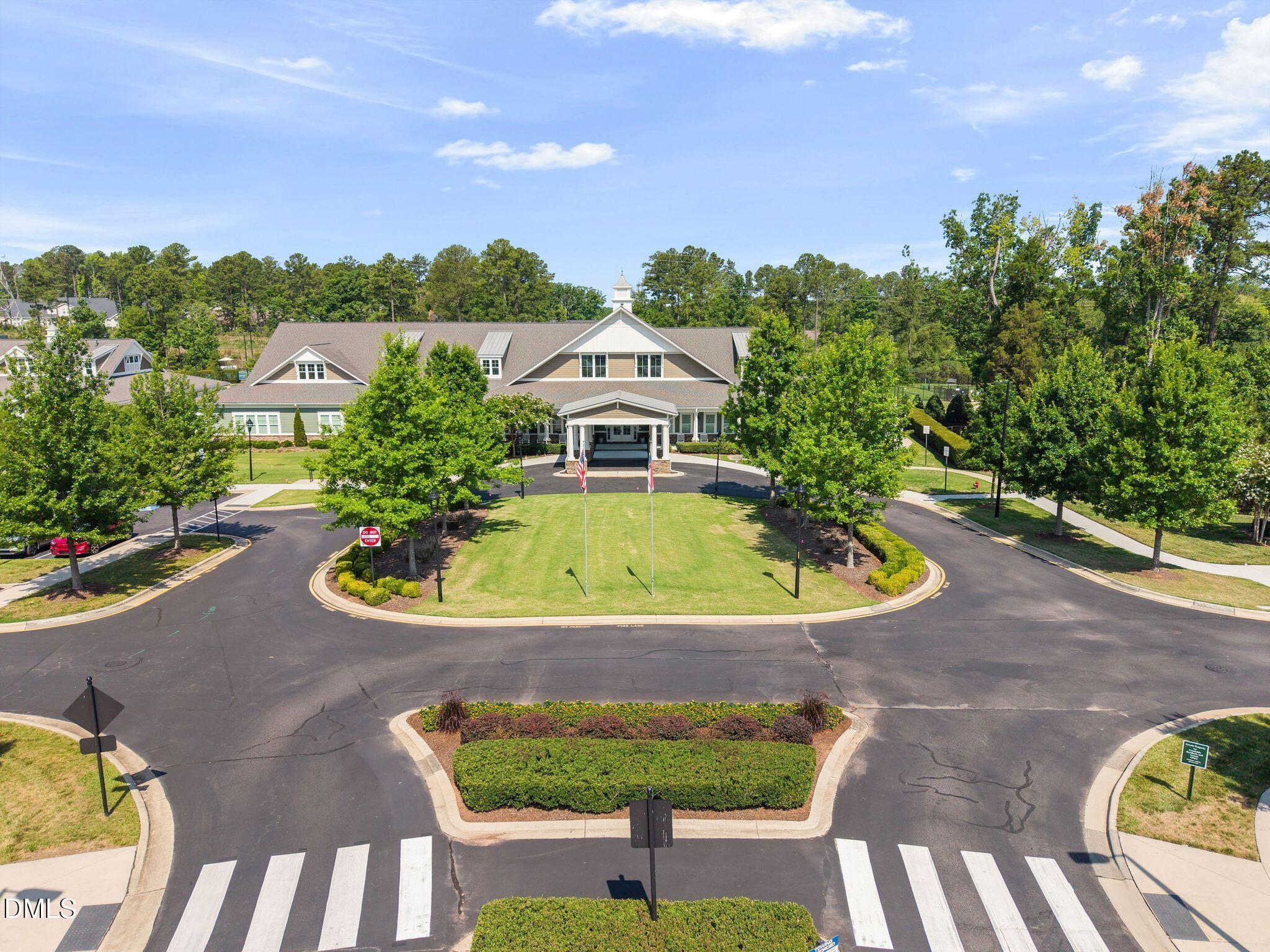 Clubhouse with a covered entrance and landscaped circular driveway, seen from above.