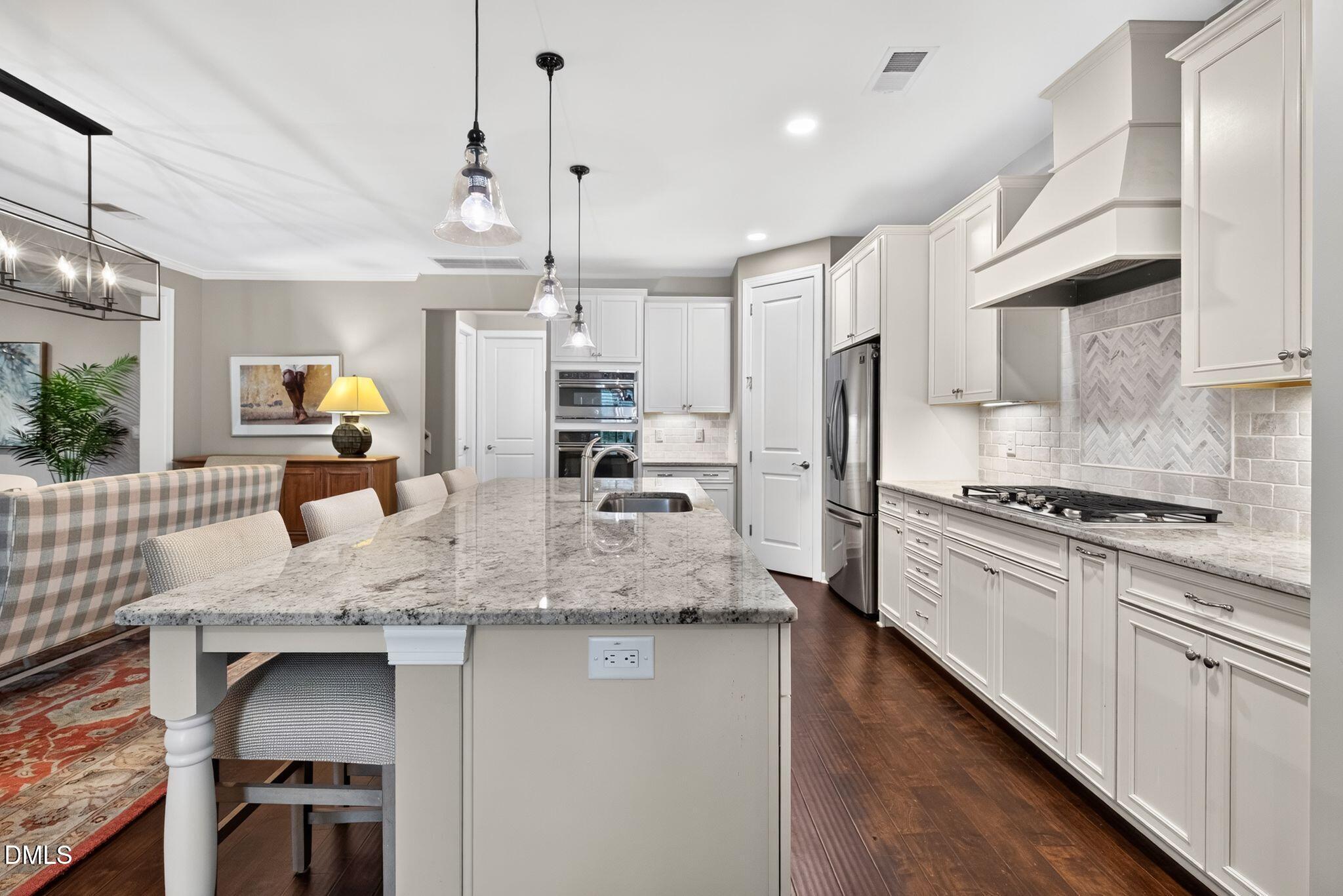 Kitchen with a large veined-stone island, white cabinetry, stainless steel appliances, and an adjoining dining nook.