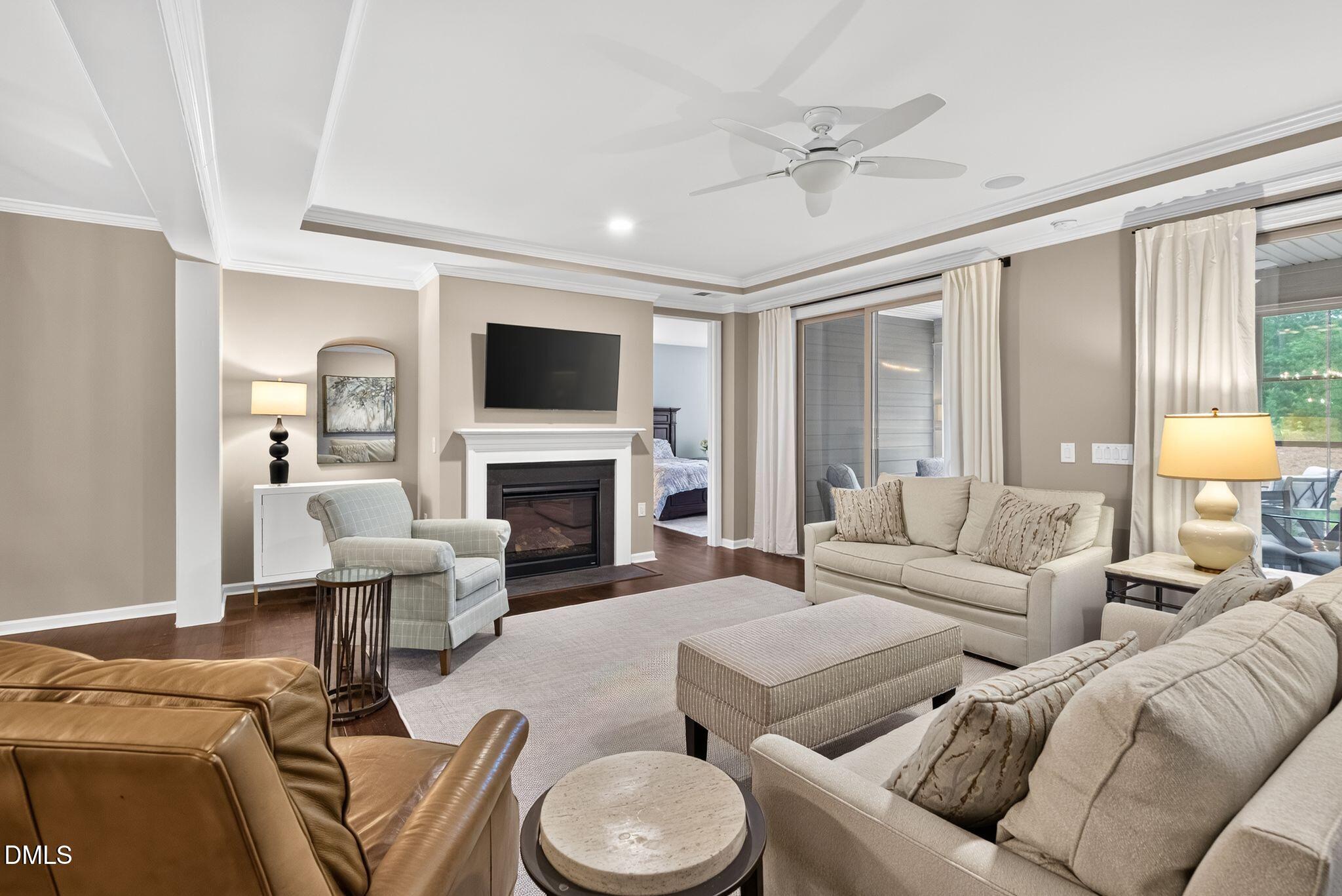 Furnished living room with a white fireplace, wall-mounted television, and sliding glass doors.