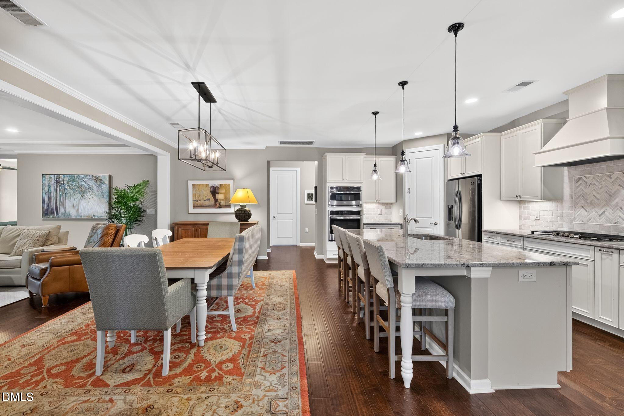 Open-plan kitchen and dining area with a large granite island, white cabinetry, and wood dining table.