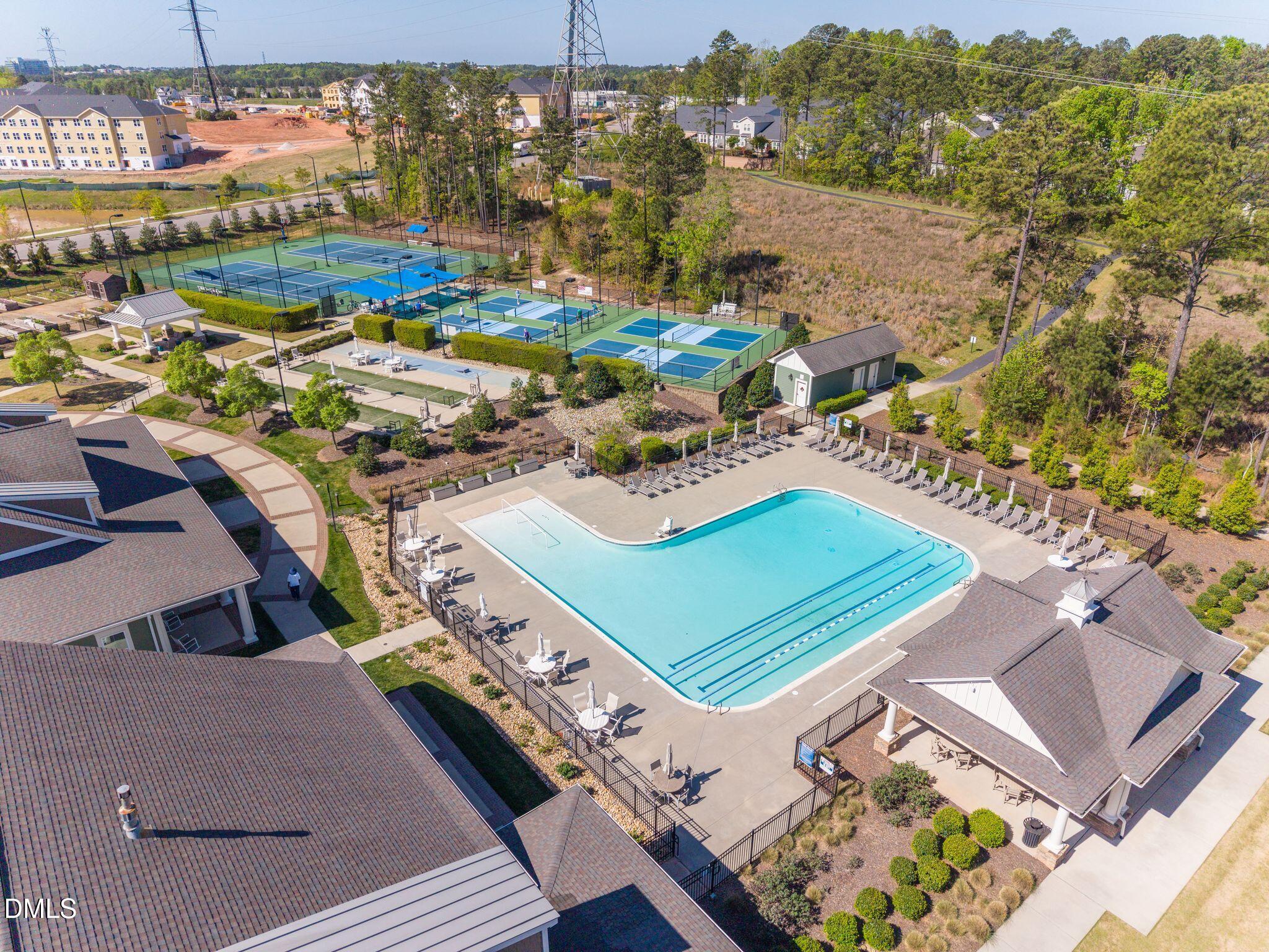 Aerial view of a community pool and fenced tennis and pickleball courts.