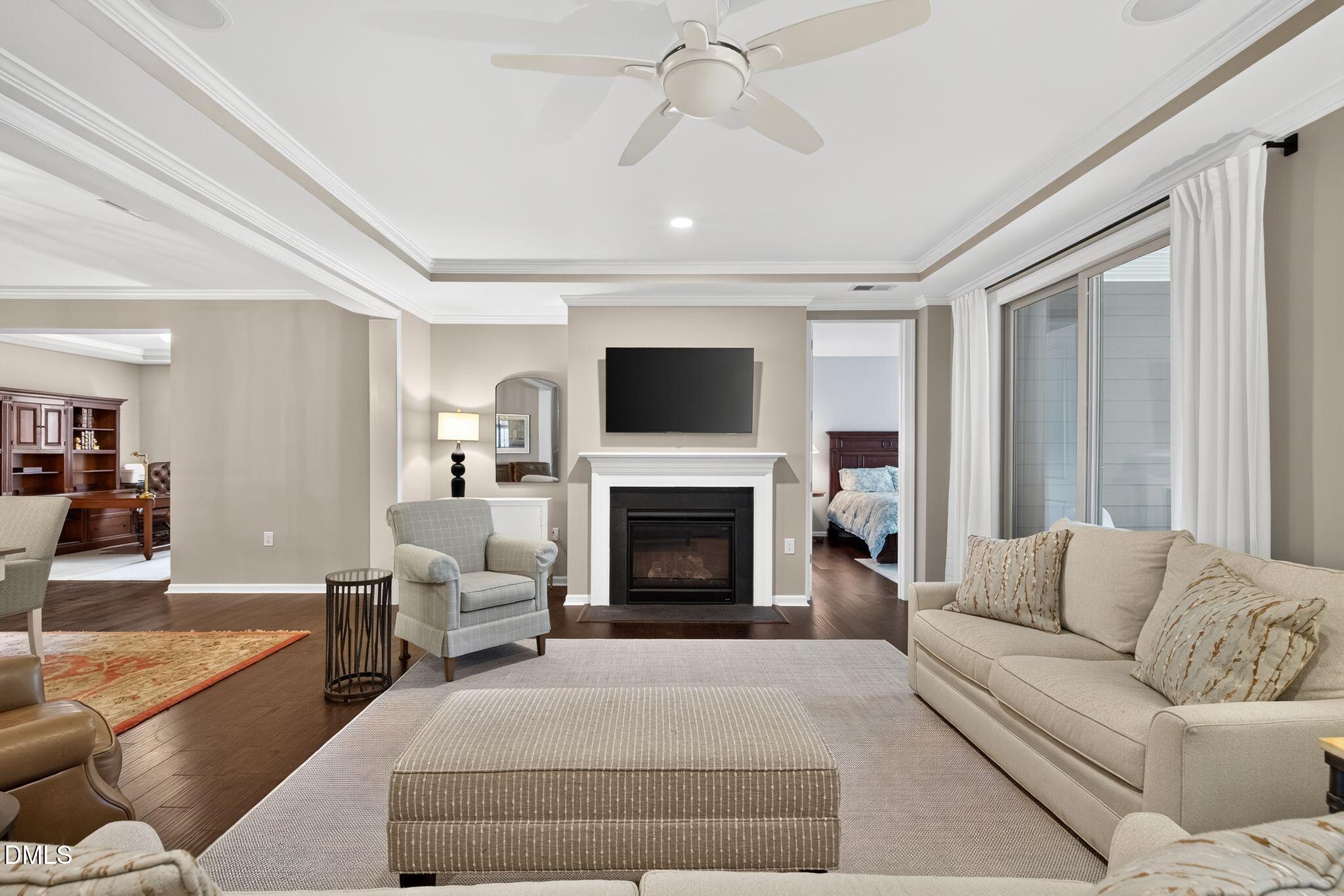 Living room with a white fireplace, wall-mounted TV, beige seating, and sliding glass doors.