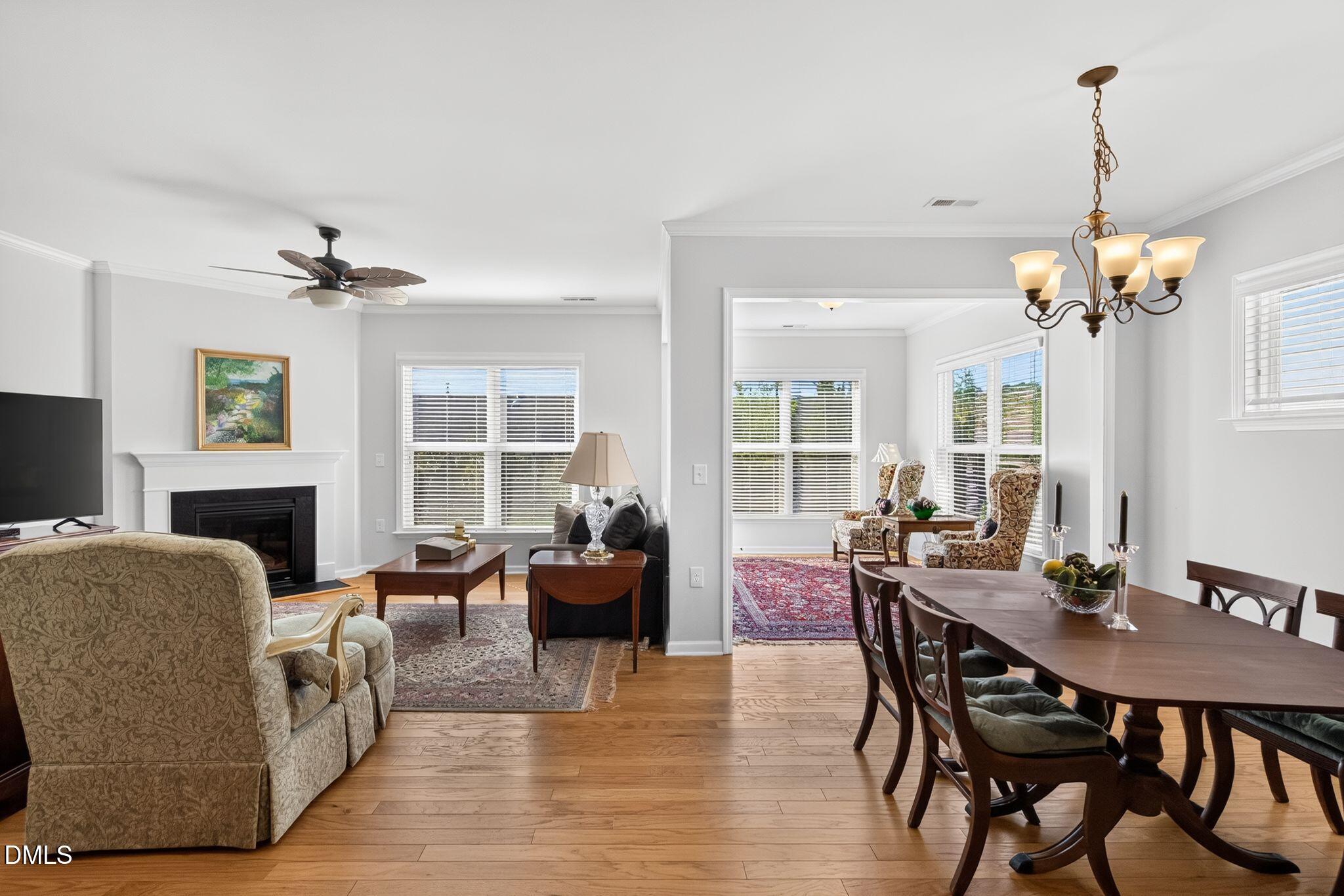 Open-plan living and dining room with hardwood floors, a fireplace, and a chandelier over the dining table.