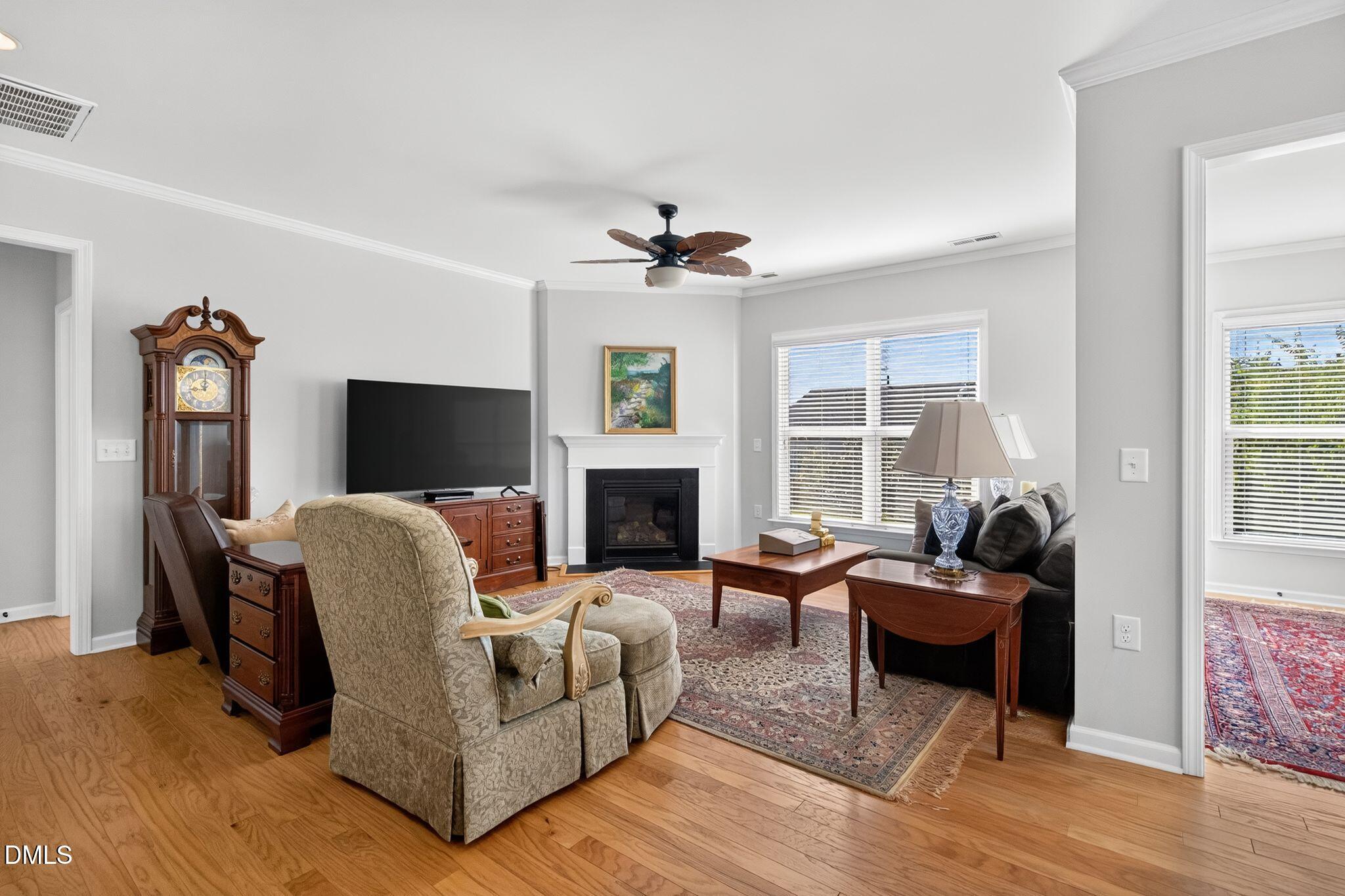 Furnished living room with hardwood floors, a fireplace, and large windows.