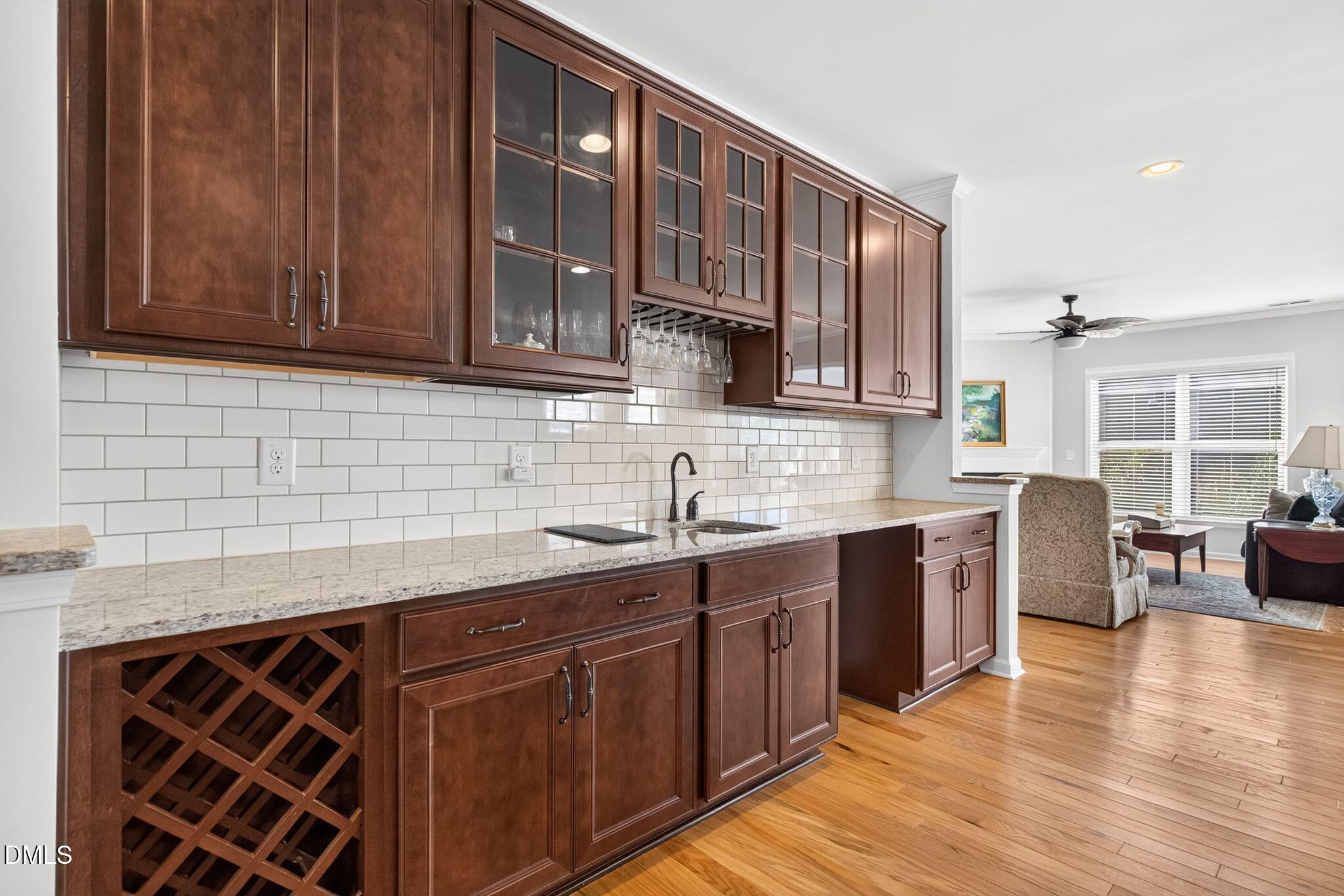 Kitchen with dark wood cabinets, subway tile backsplash, granite counters, and a built-in wine rack.