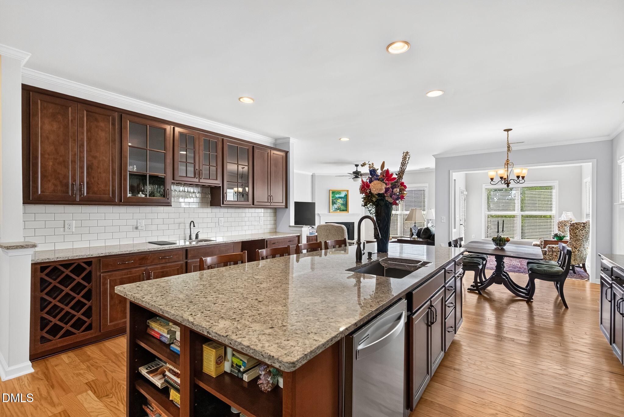 Kitchen with dark wood cabinets and a granite island opening to a dining area.