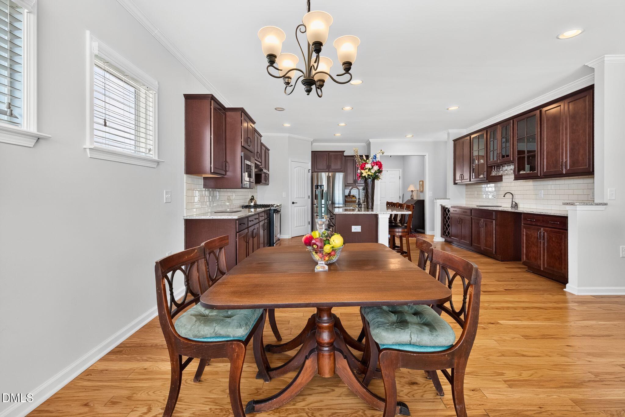 Dining table in a spacious kitchen with dark wood cabinets, a central island, and hardwood floors.