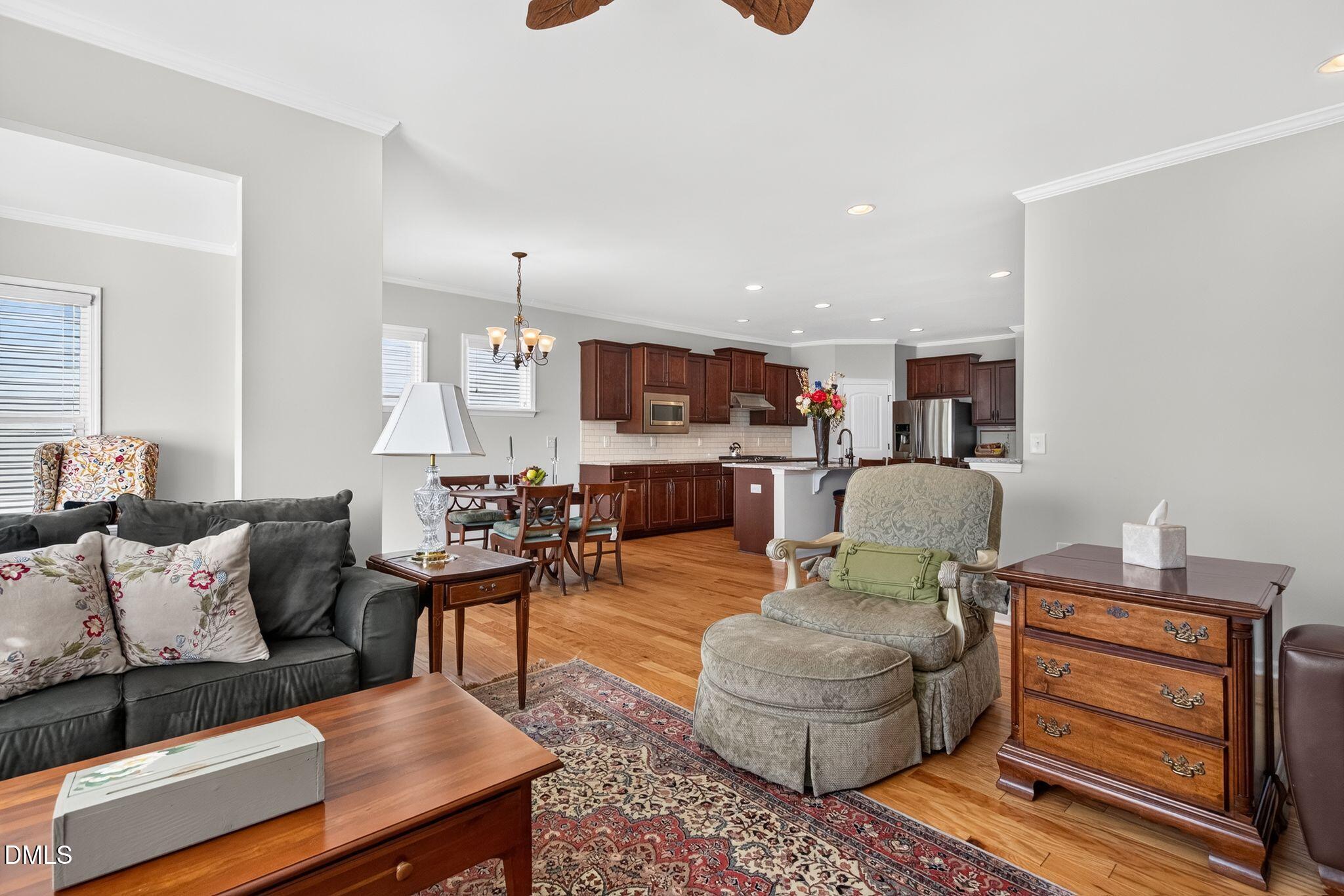 Open-plan living room and kitchen with hardwood floors, dark wood cabinets, and a gray sofa.