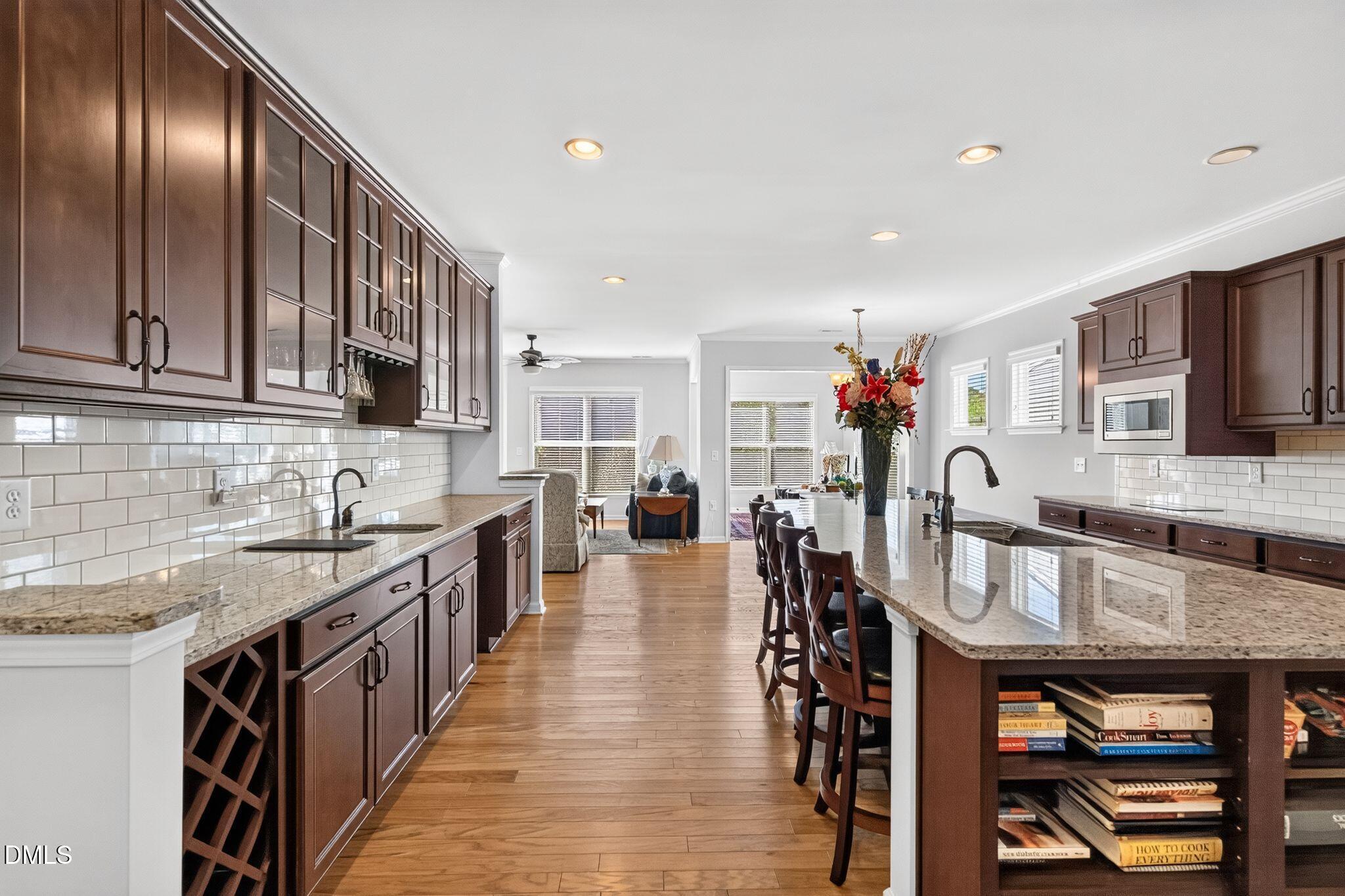 Kitchen with dark wood cabinets, granite counters, subway tile backsplash, and a large island with bar seating.