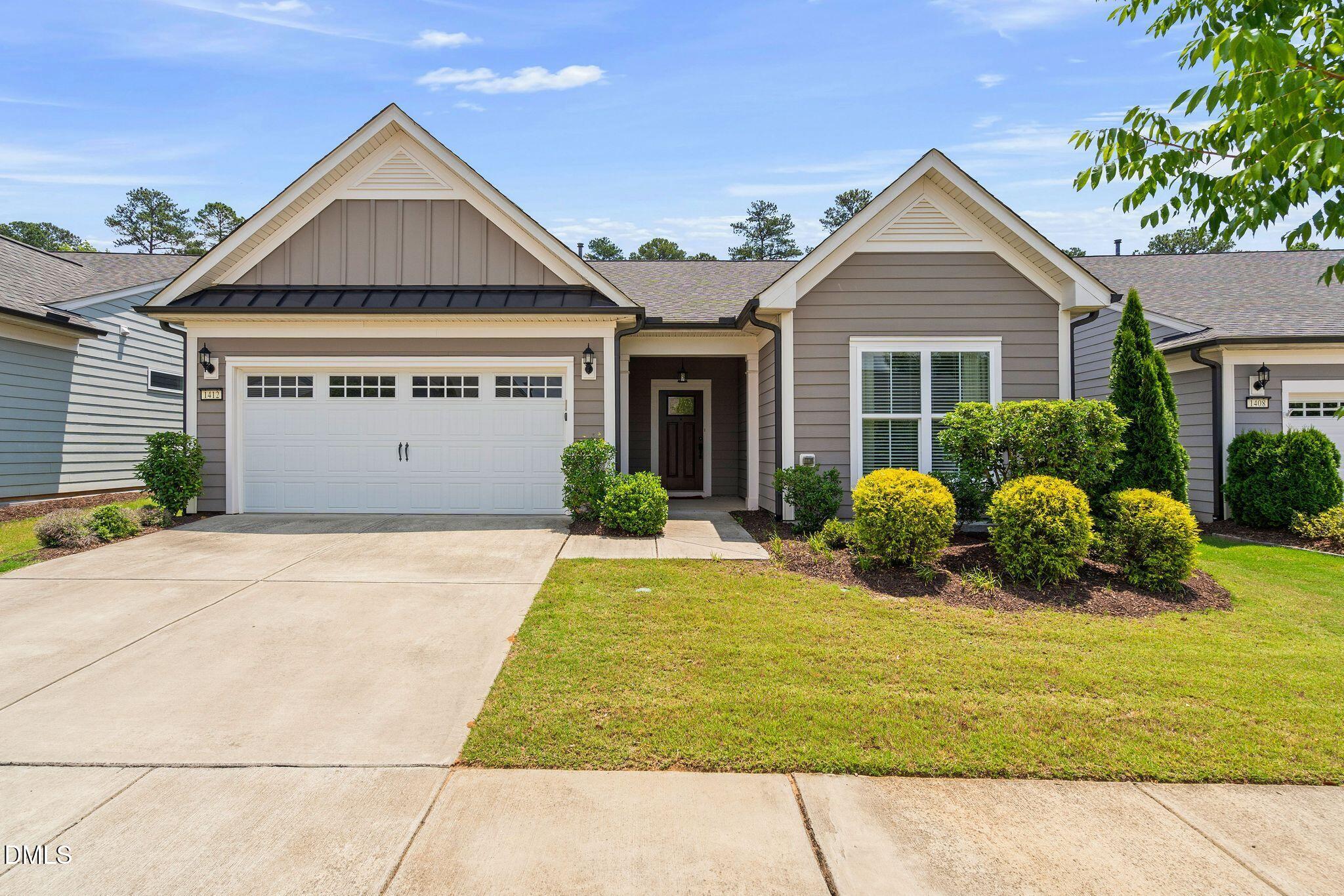 Gray single-story home with twin front gables, white garage door, and landscaped shrubs.