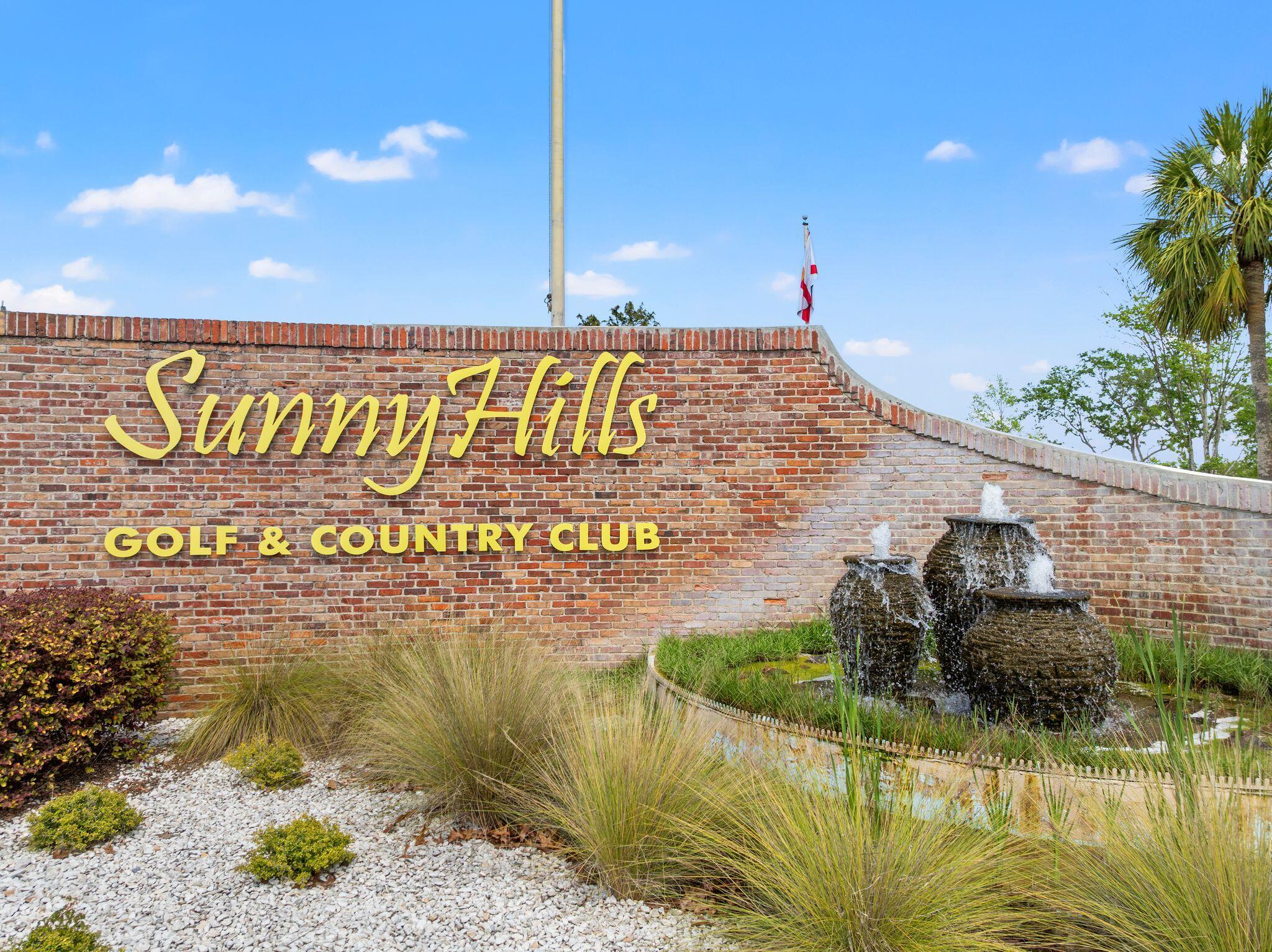 Sunny Hills Golf & Country Club entrance sign beside a landscaped fountain.