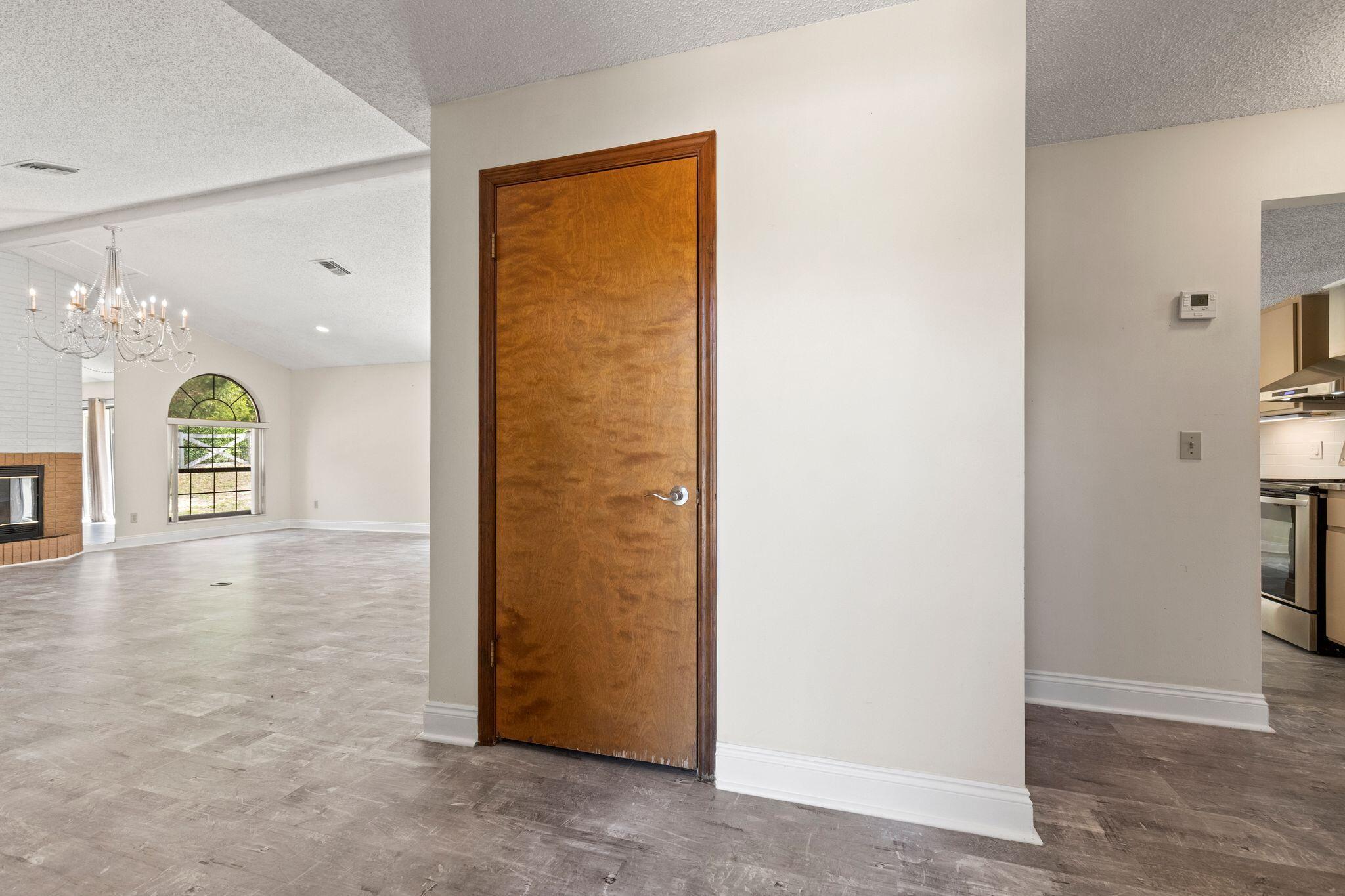 Vacant living area with tiled floors, a brick fireplace, arched window, and chandelier.