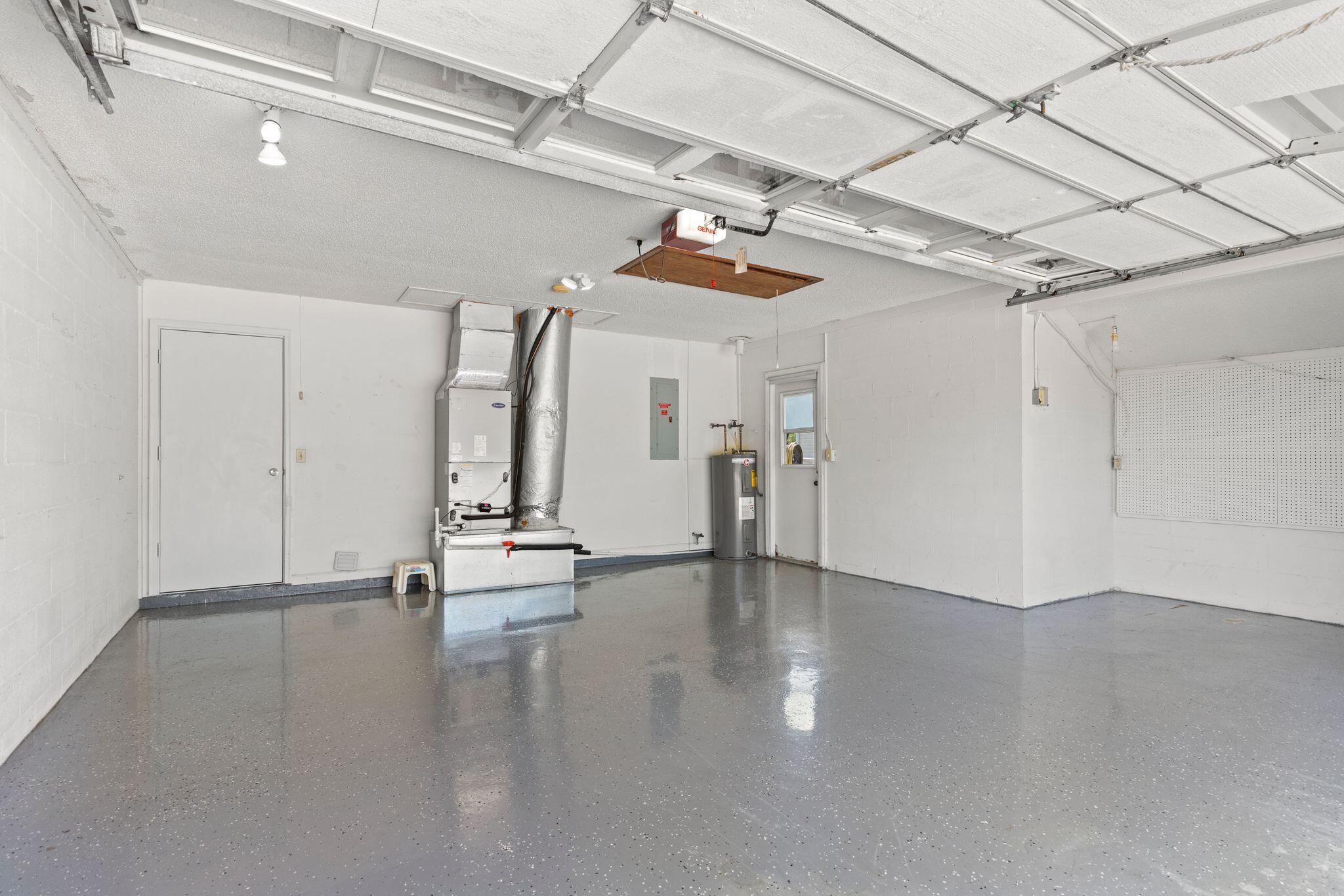 Empty garage with a glossy speckled floor, overhead door, HVAC system, and water heater.