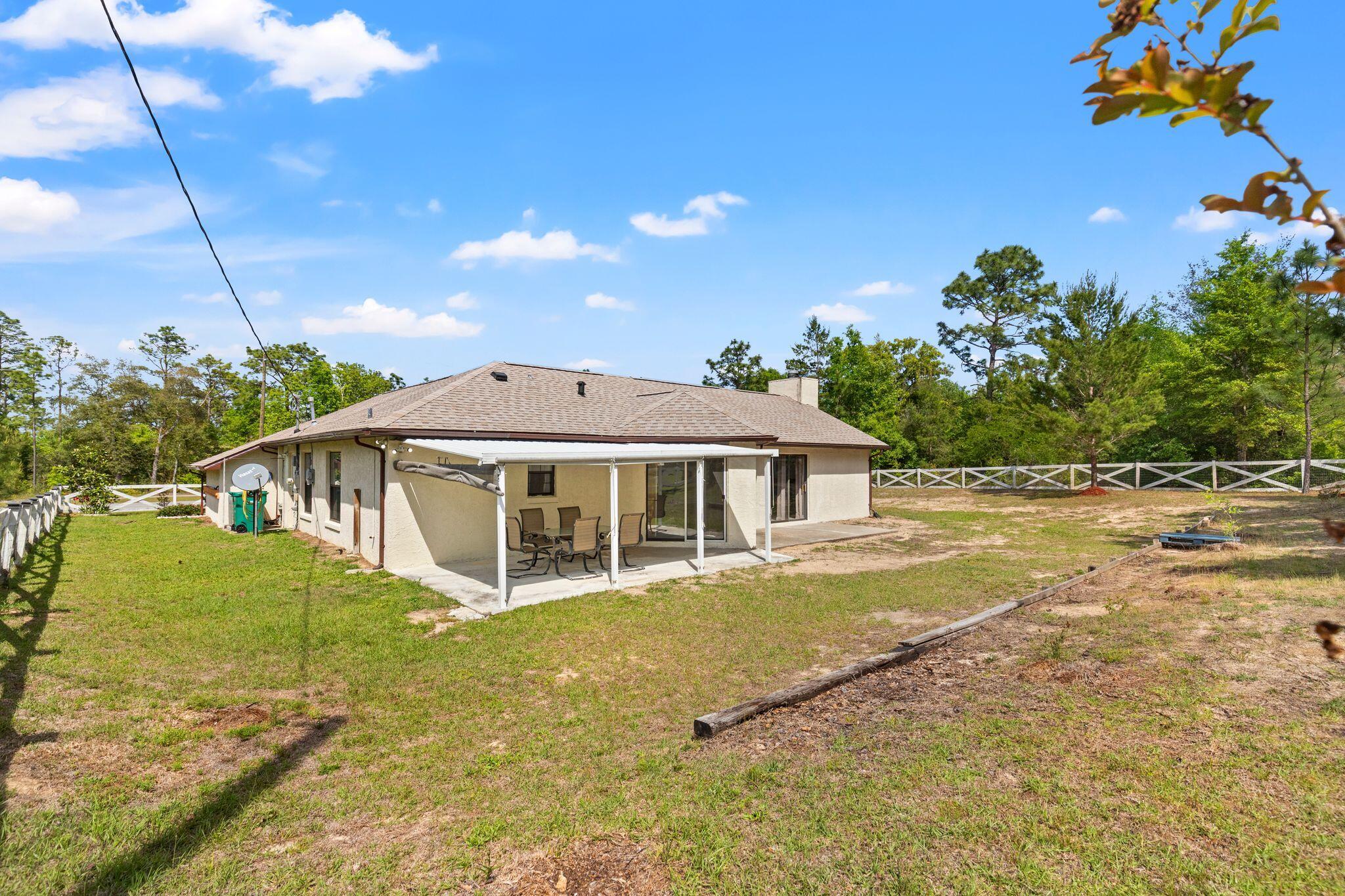 Rear of a single-story home with a covered patio and fenced yard.