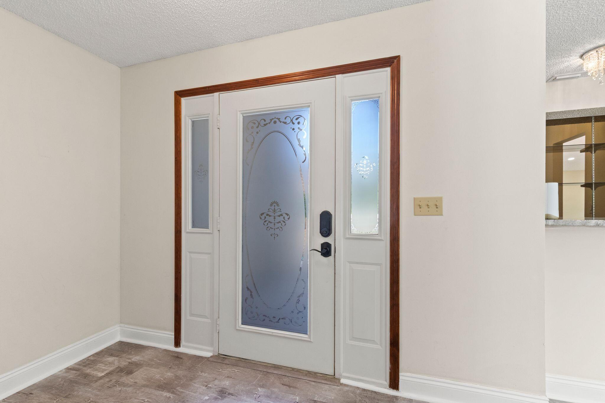 Entryway with a white front door featuring decorative frosted glass and dark hardware.