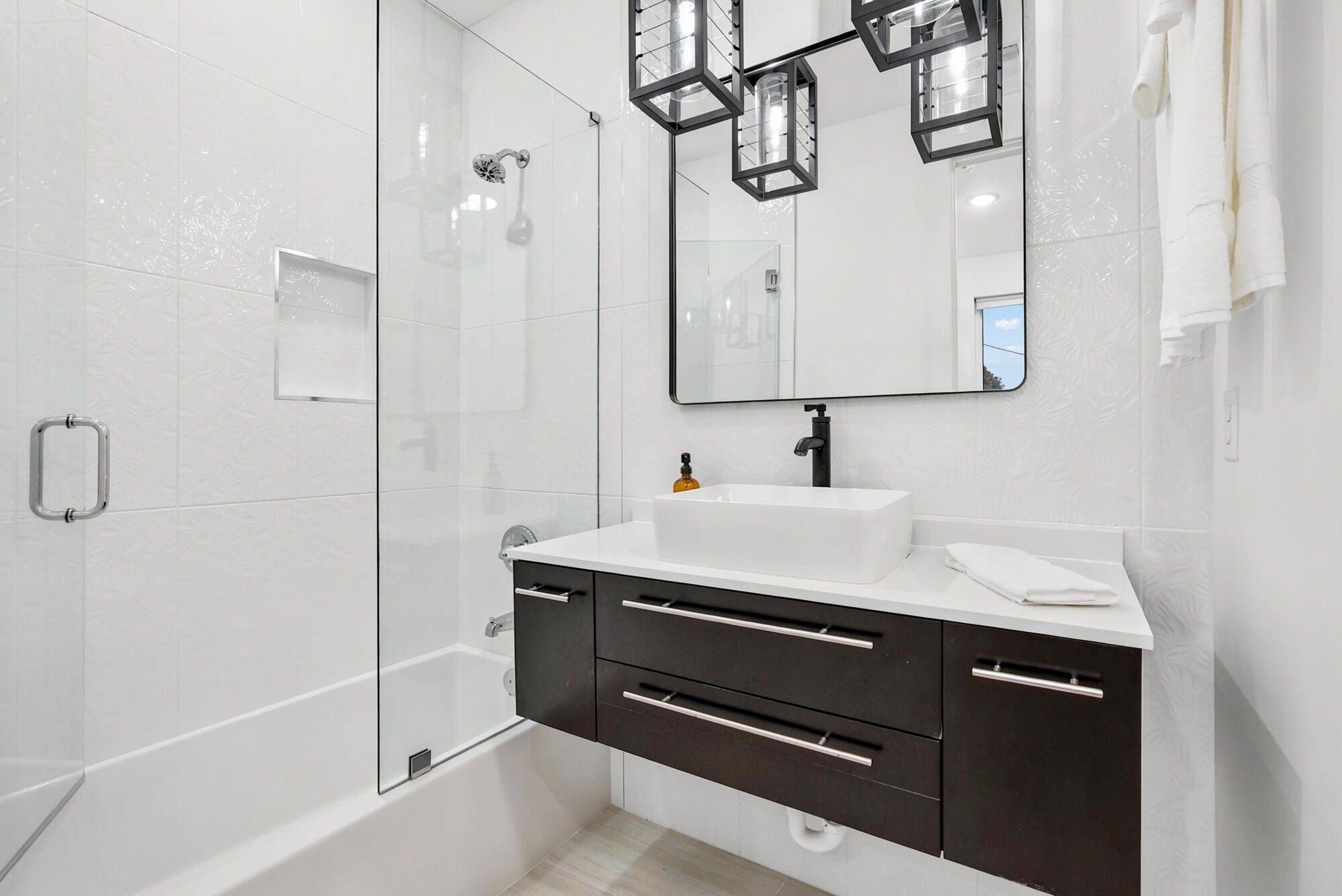 Modern bathroom with a glass-enclosed shower and dark floating vanity with a vessel sink.